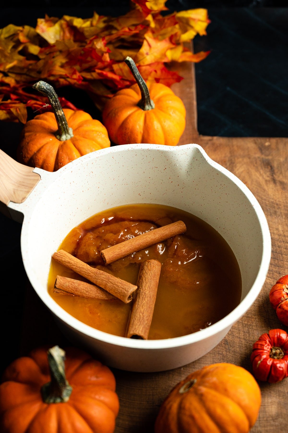 The pumpkin butter, maple syrup, water, and cinnamon in a small white pot.