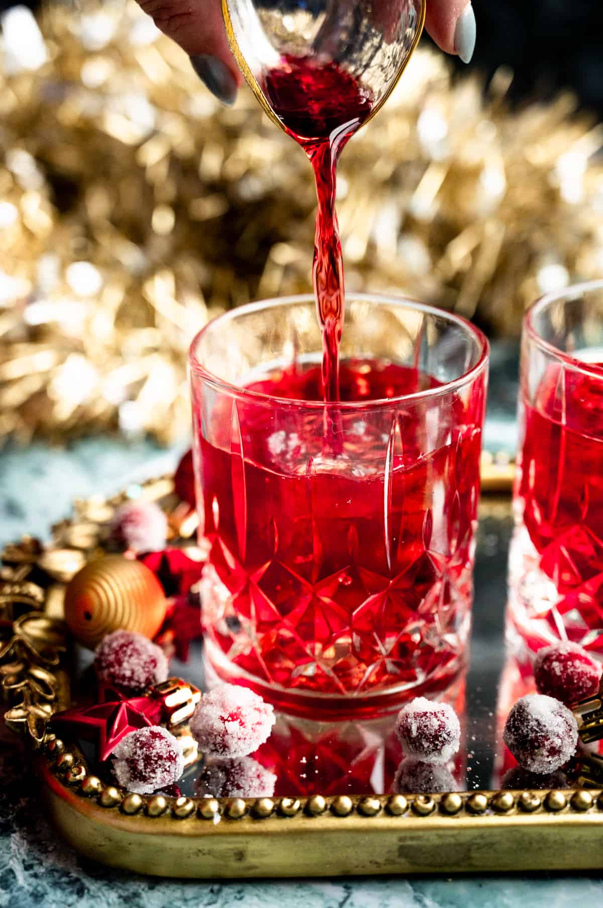 The cranberry juice being poured into the glass.