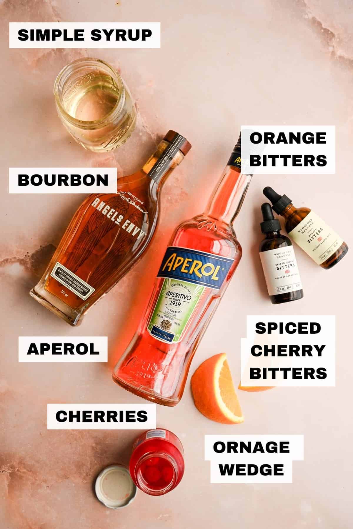 The ingredients for the aperol spritz on a pink marble table.