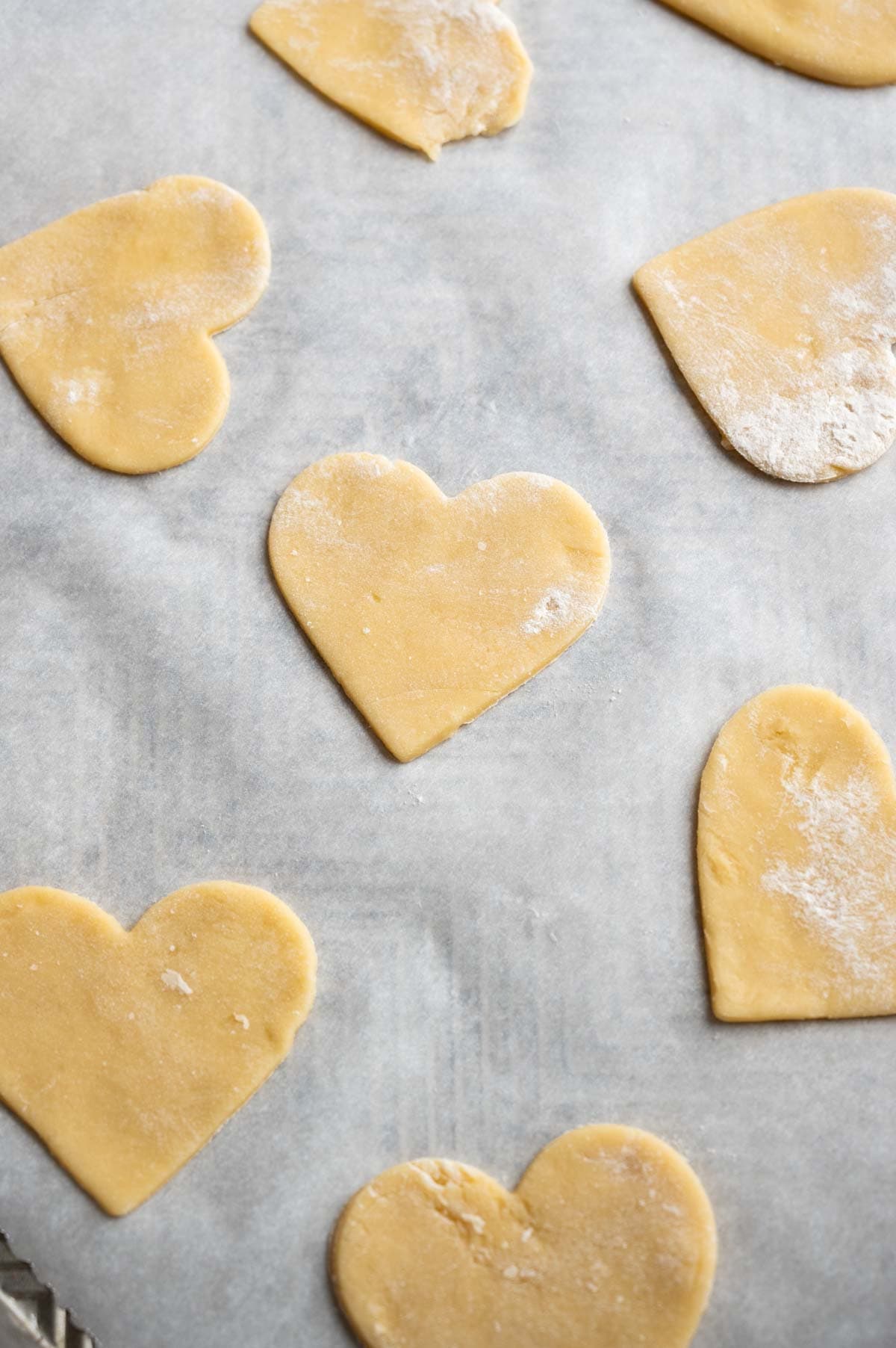The cut out hearts sitting on a lined baking sheet.