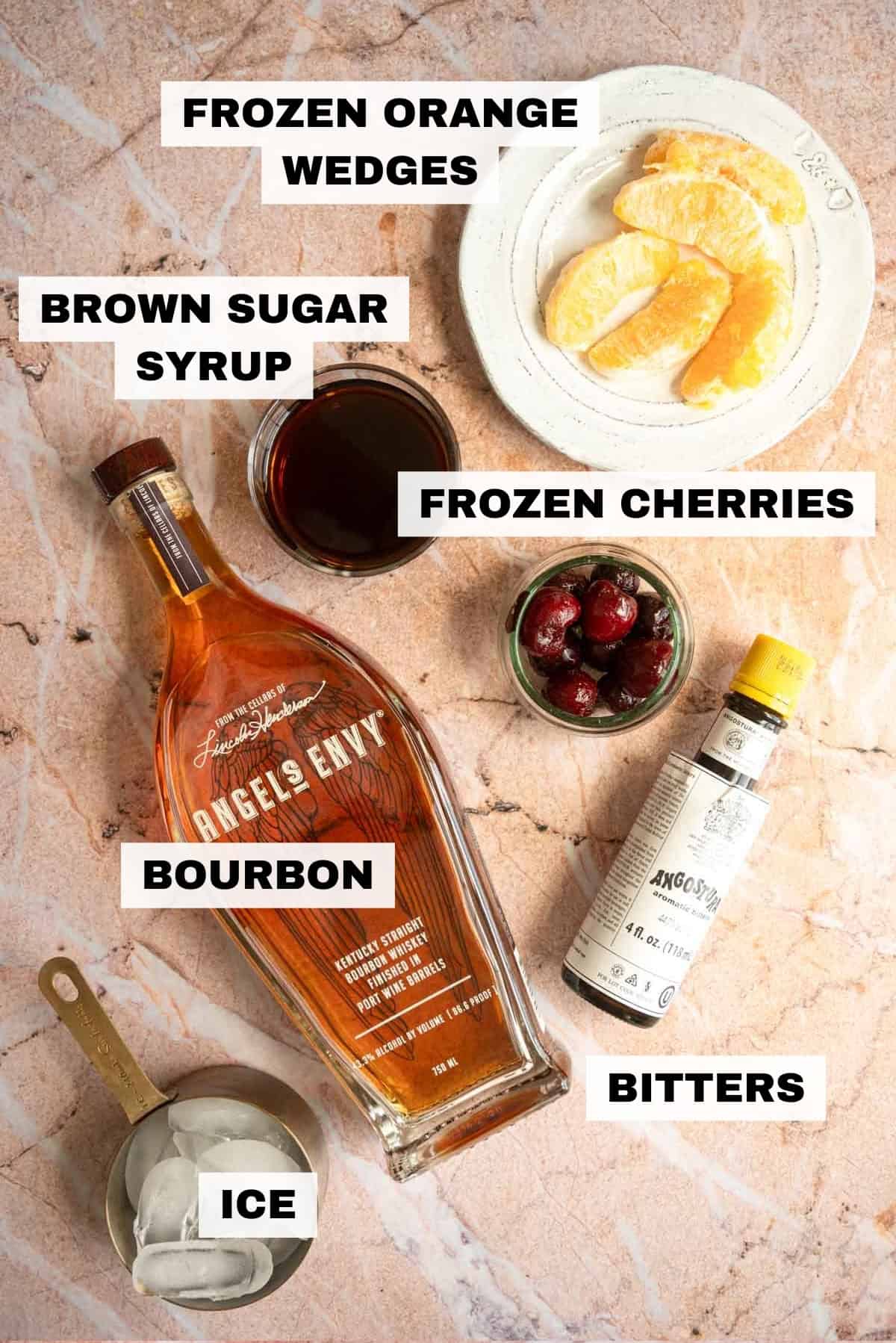 The ingredients for the frozen old fashioned on a pink marble table.