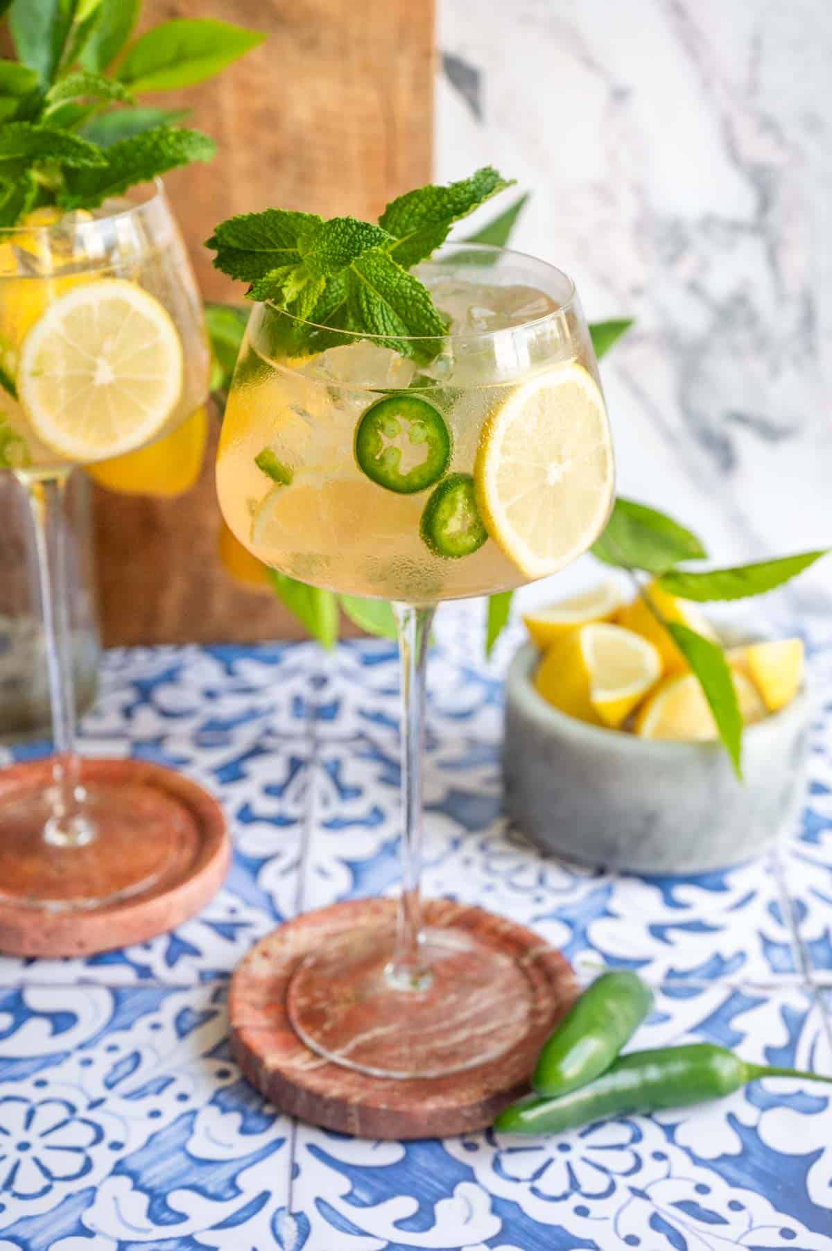 Long stem spritz glasses filled with the cocktail and garnished with lemons and fresh mint.