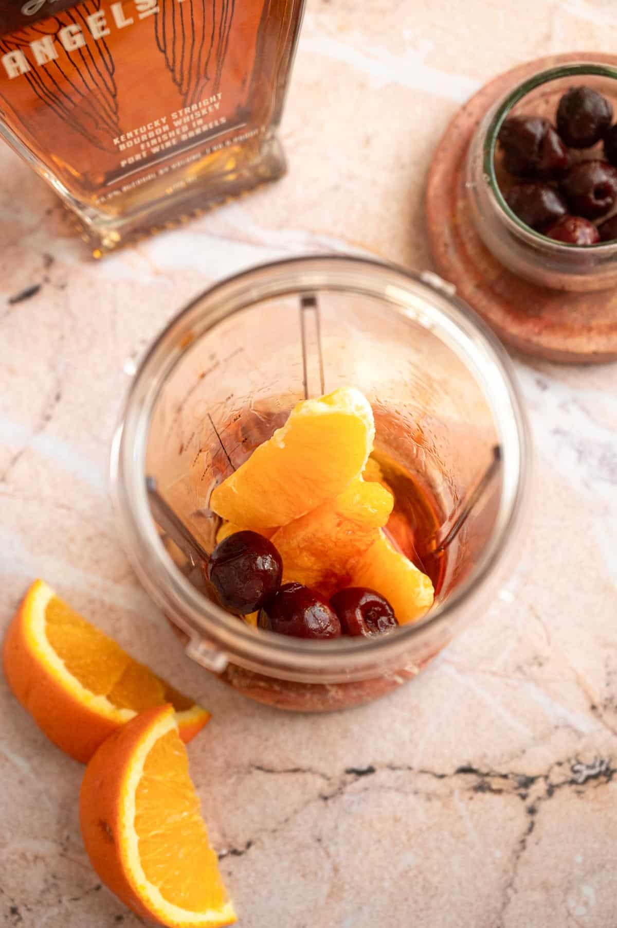 The oranges, cherries, bourbon, syrup, and bitters in a blender.