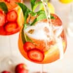 Stawberry Lone Ranger in a spritz glass garnished with mint, strawberries and lemon with sparkling Wien bering poured on top.