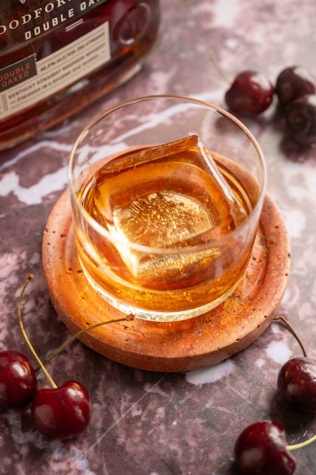 A small rocks glass with an ice cube and bourbon.