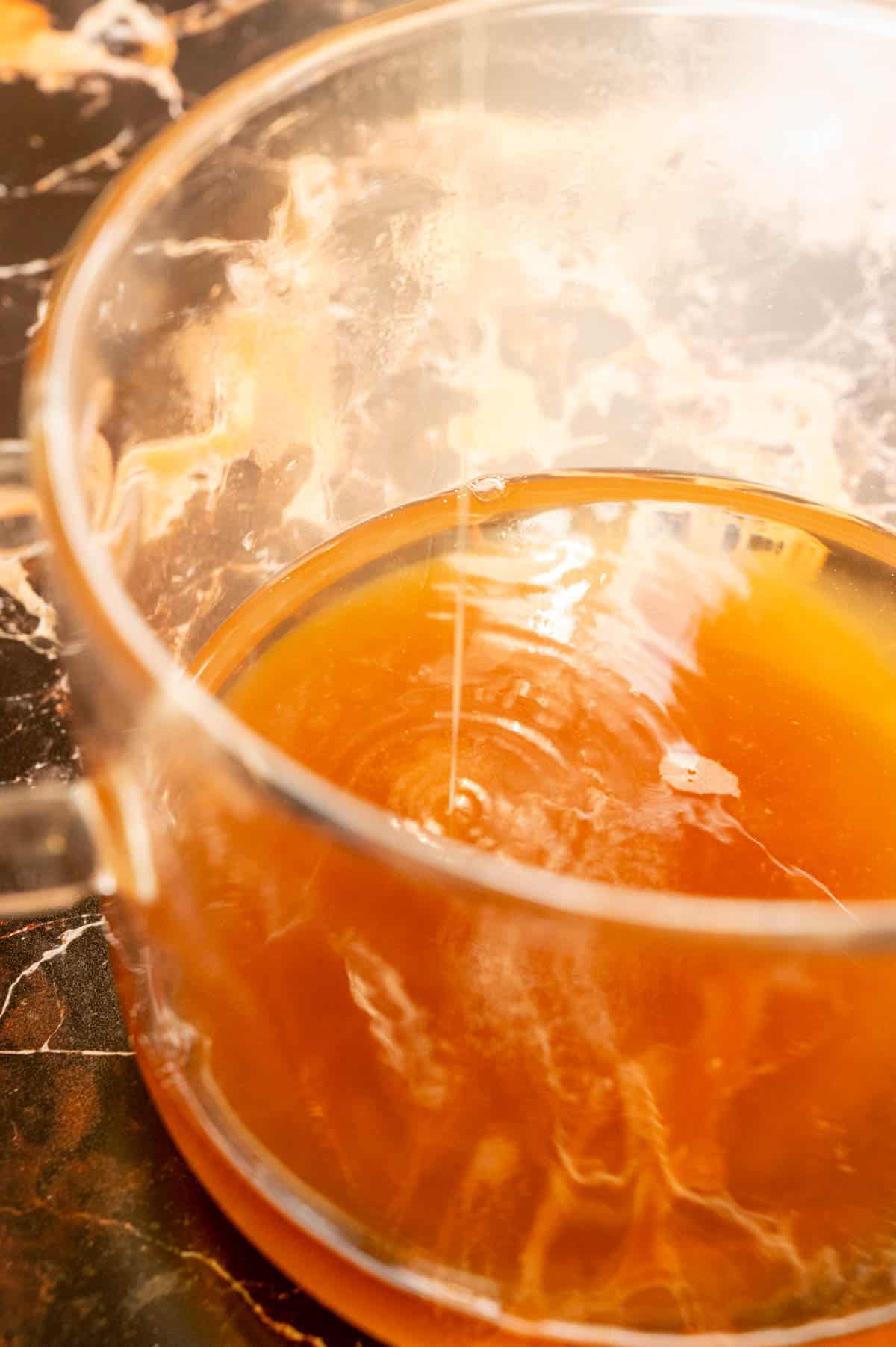 a clear glass pot filled with the cream soda and the butterscotch syrup being poured in.