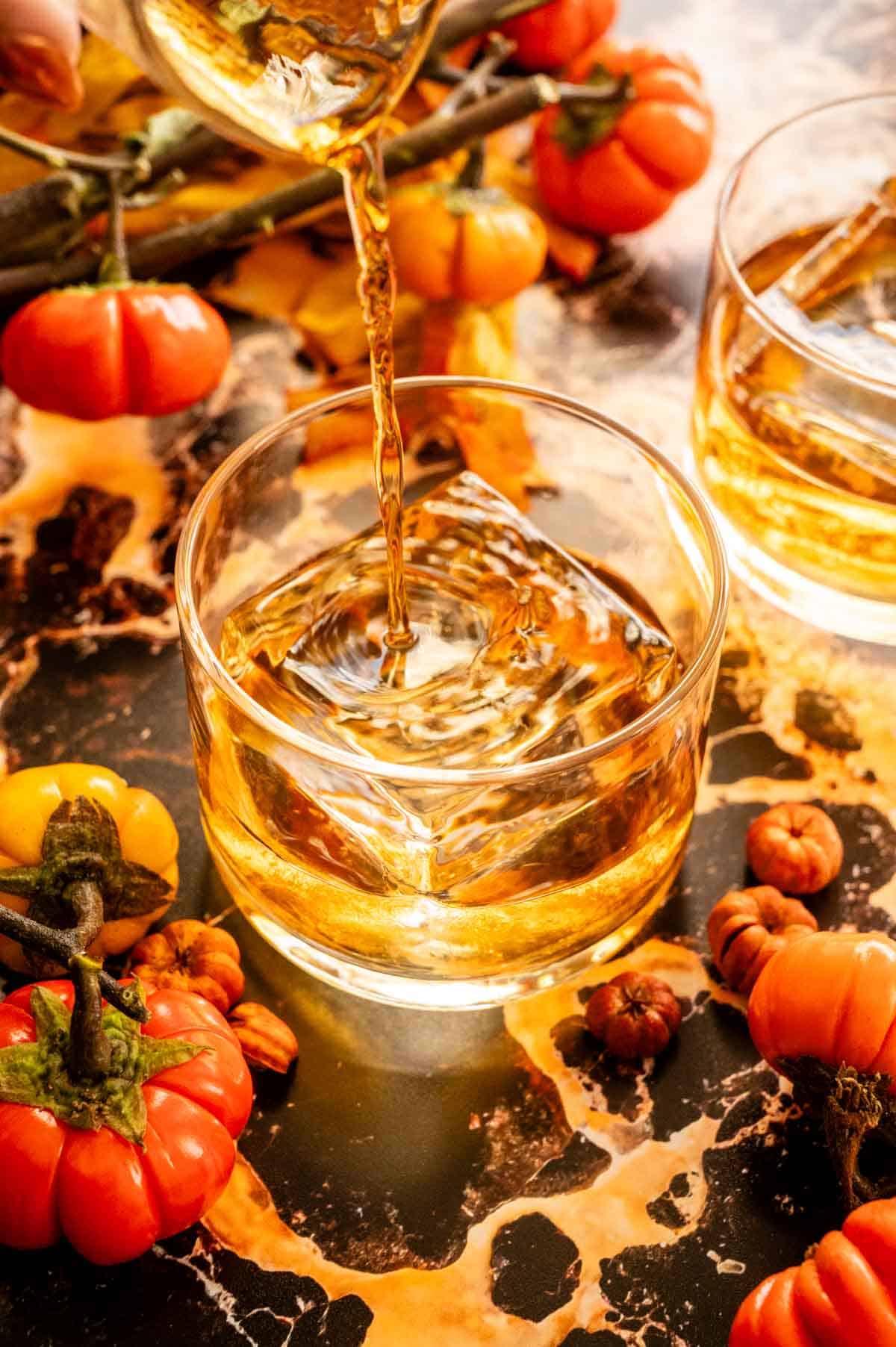 The bourbon being poured into a rocks glass with one large ice cube.