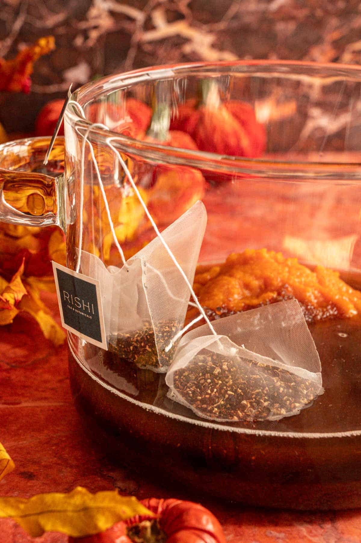 The syrup ingredients in a clear glass pot on an orange marble table.