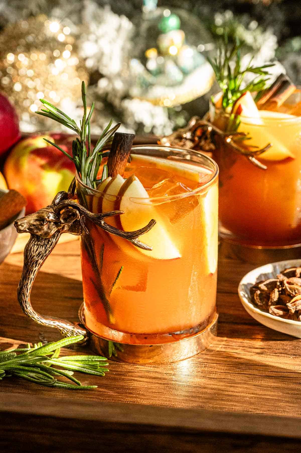 An apple butter old fashioned in a glass with a stag handle on a wood bar cart.