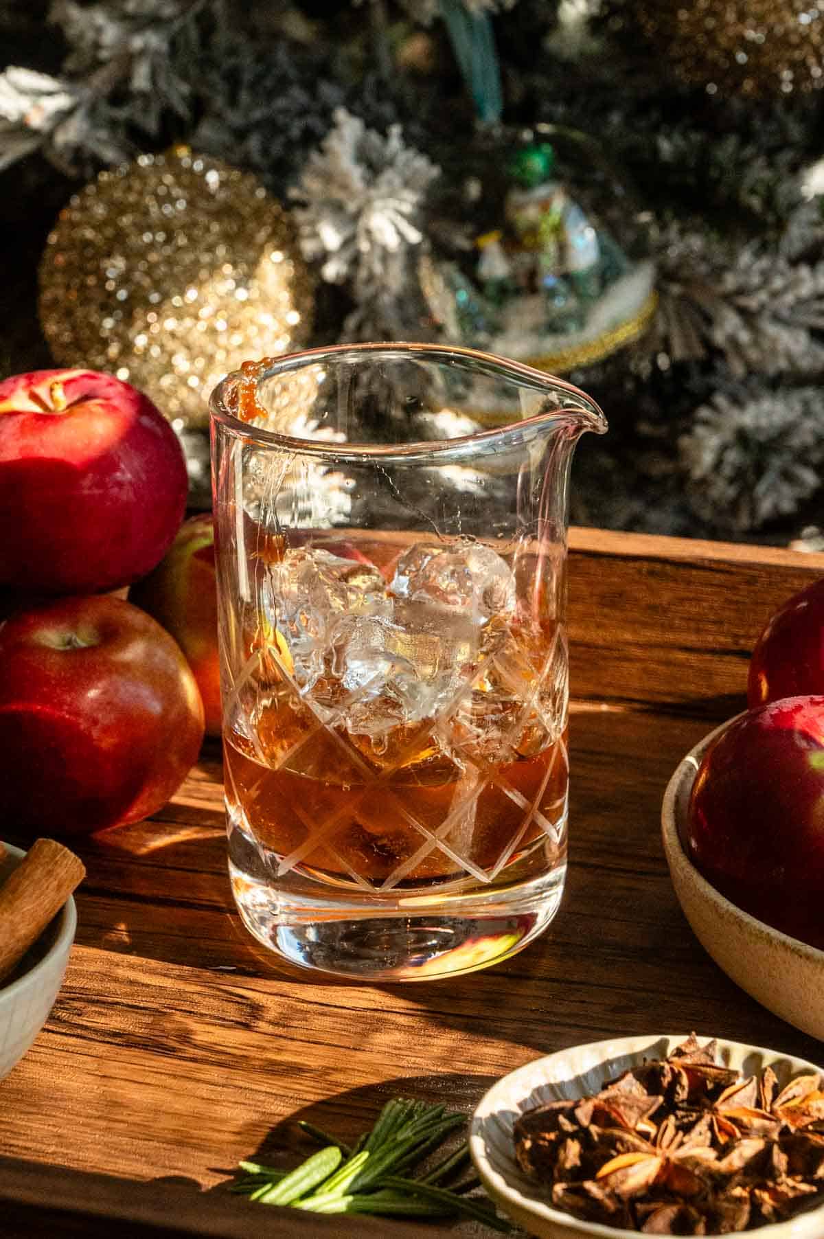 Apple butter, bourbon, and ice in a mixing glass.