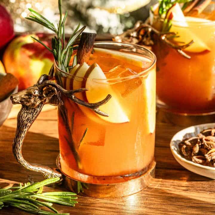 An apple butter old fashioned in a glass with a stag handle on a wood bar cart.