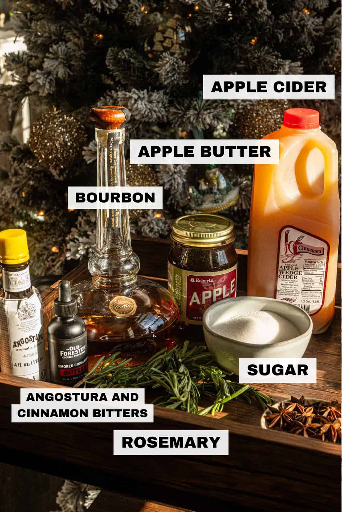 All the ingredients on a wood bar cart in front of a Christmas tree.