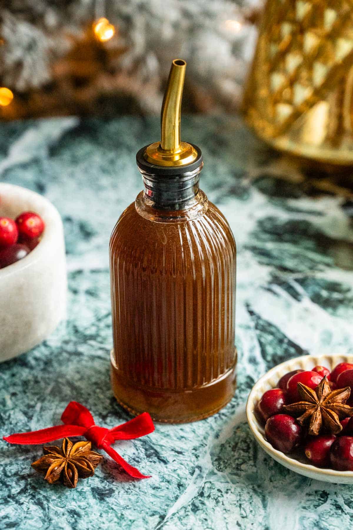 The hot honey syrup in a glass syrup container on a green marble table.