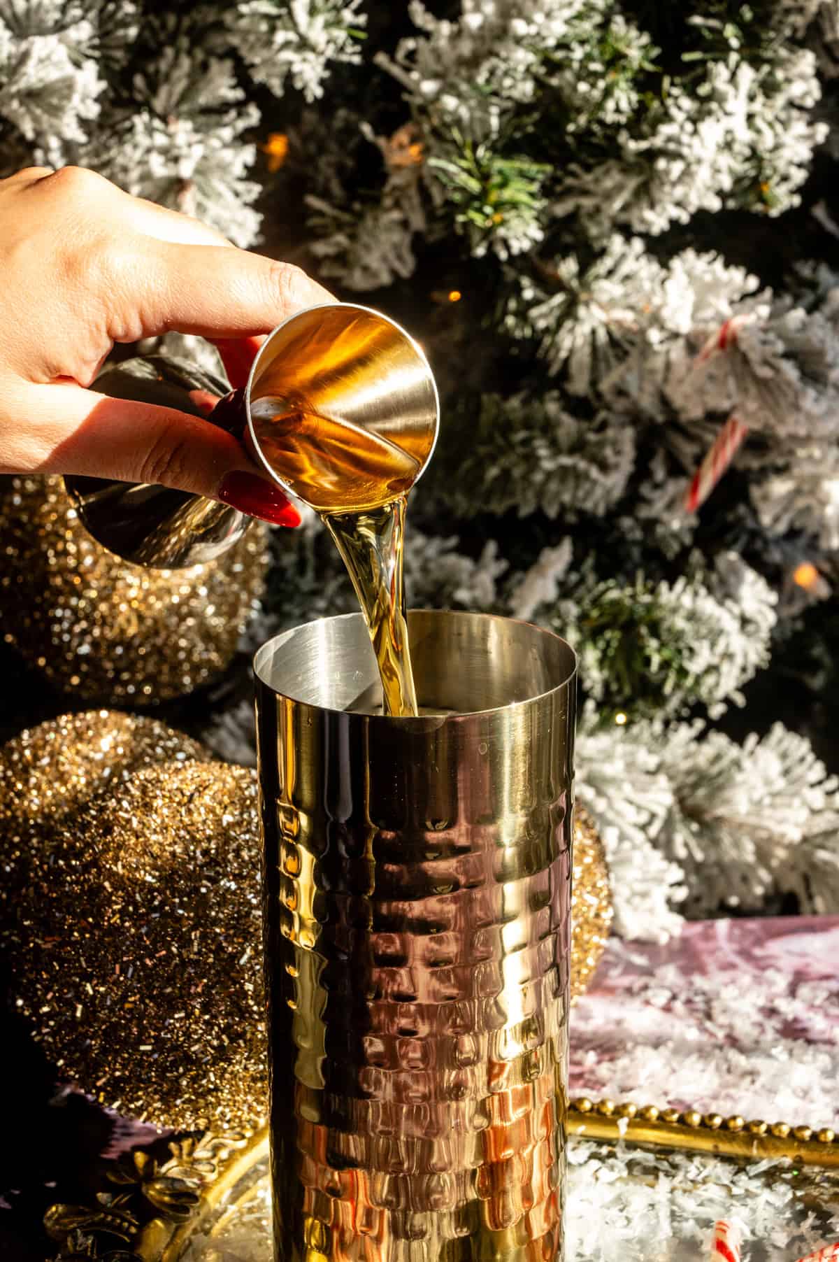 Bourbon being poured into a gold cocktail shaker.