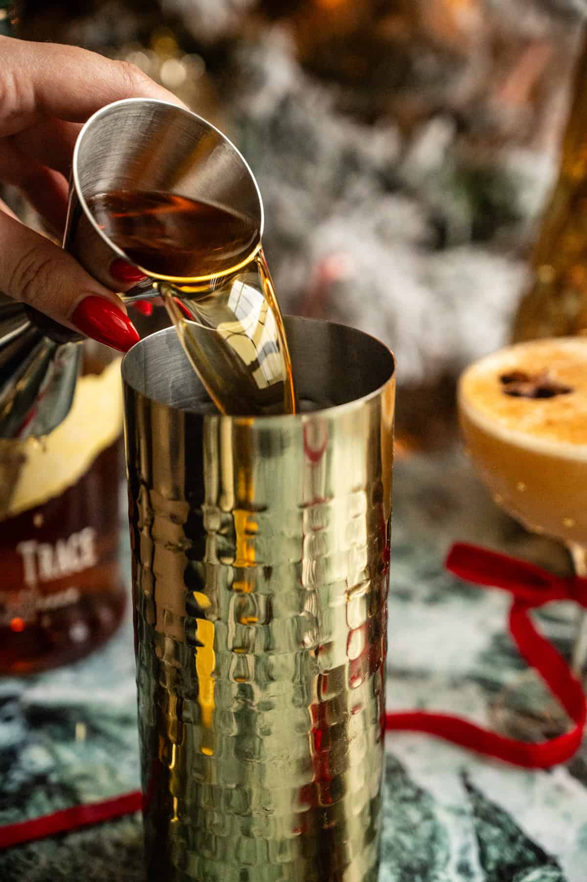 Bourbon being poured into a gold cocktail shaker.