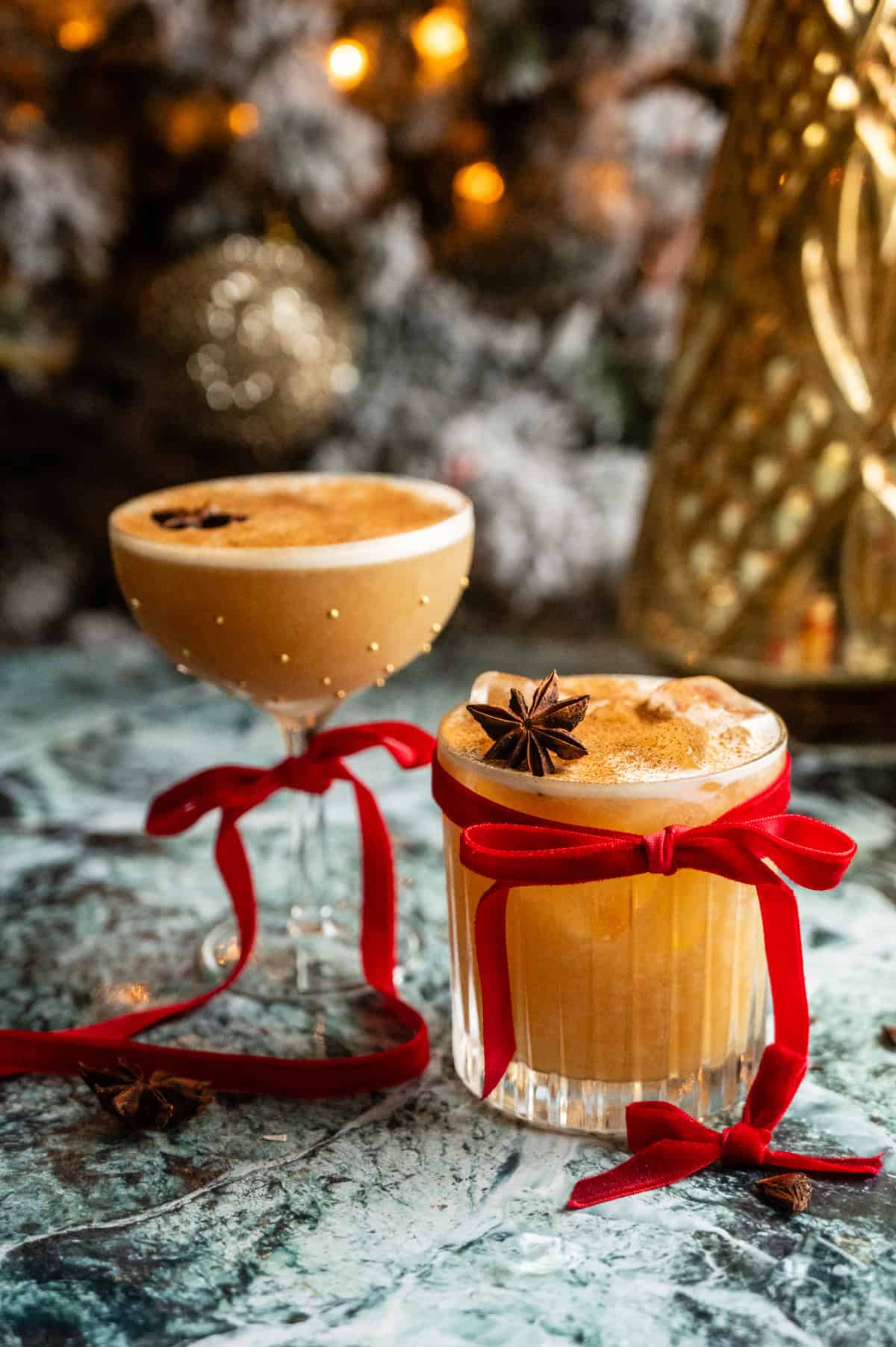 two whiskey sours, one in a coupe glass and one in a rocks glass, with red bows tied around the glass.