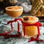 two whiskey sours, one in a coupe glass and one in a rocks glass, with red bows tied around the glass.