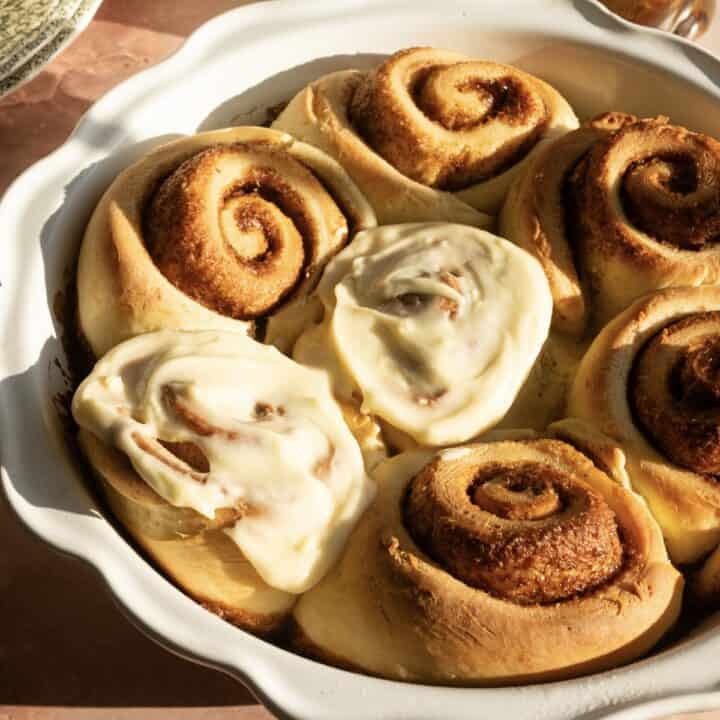 A tray of cinnamon rolls with the center and bottom left roll frosted.