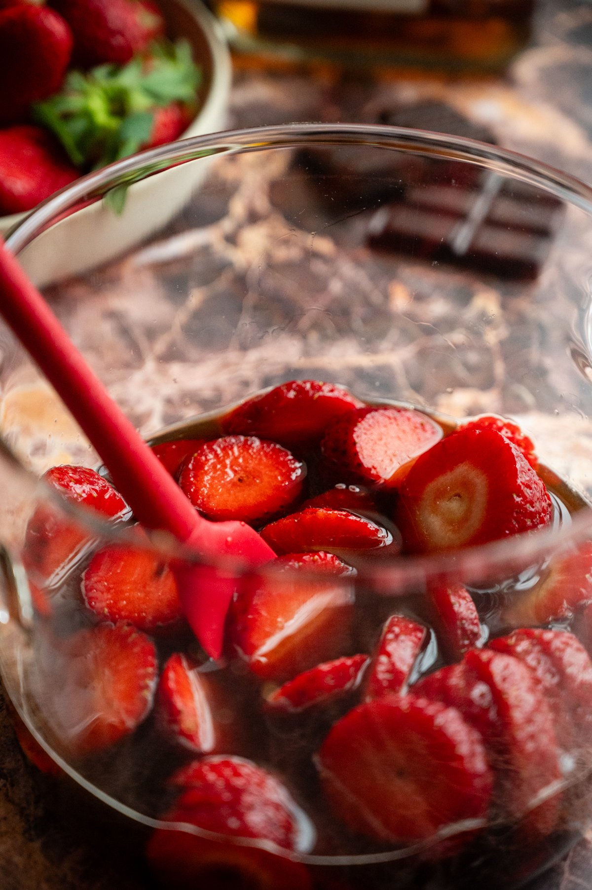 Strawberries, water, and brown sugar mixed together in a glass pot.