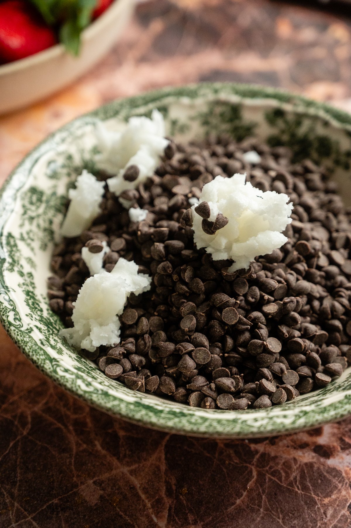 Mini semi-sweet chocolate chips and coconut oil in a green and white bowl.