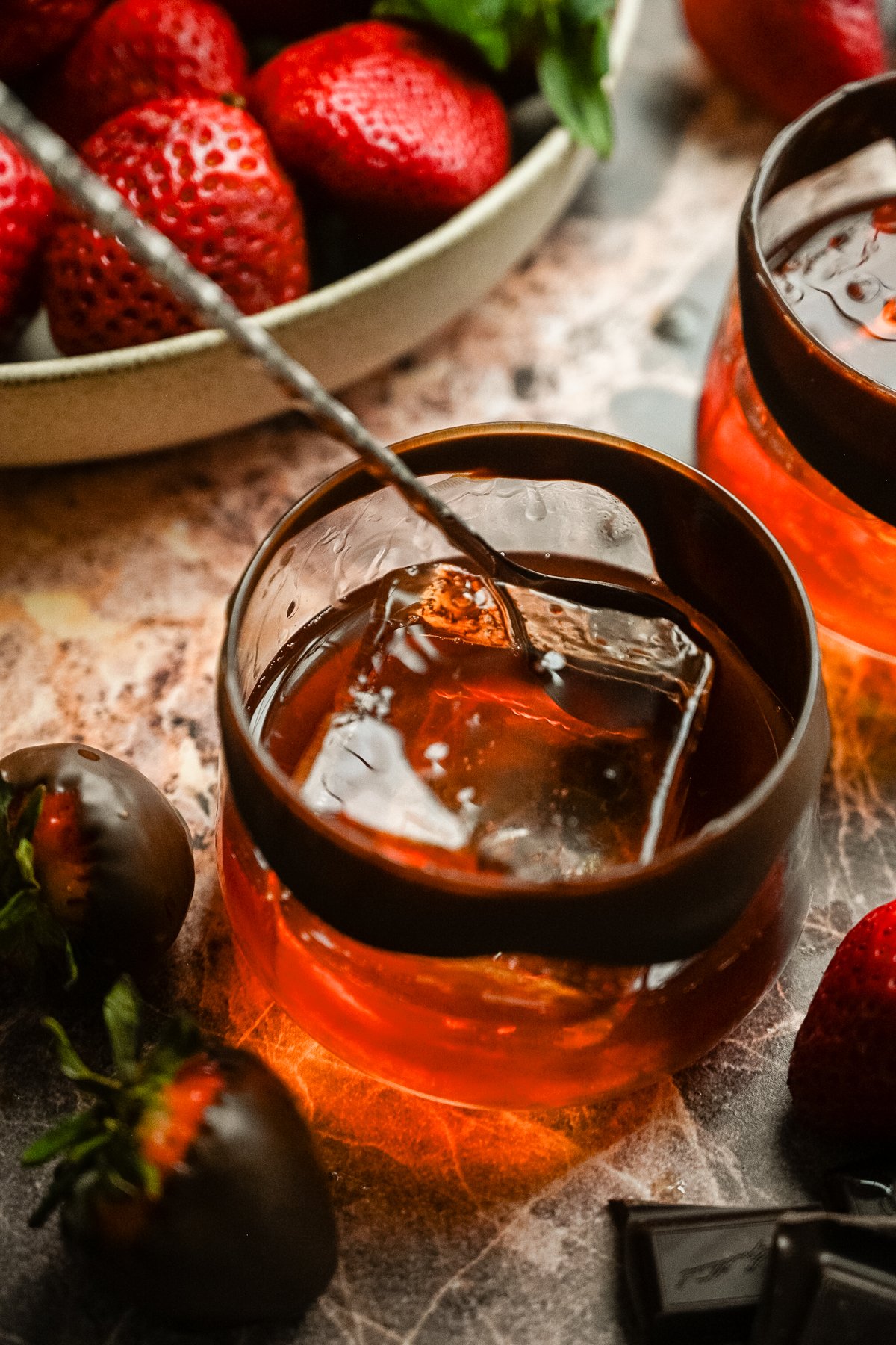 A cocktail stirrer is stirring the drink from above.