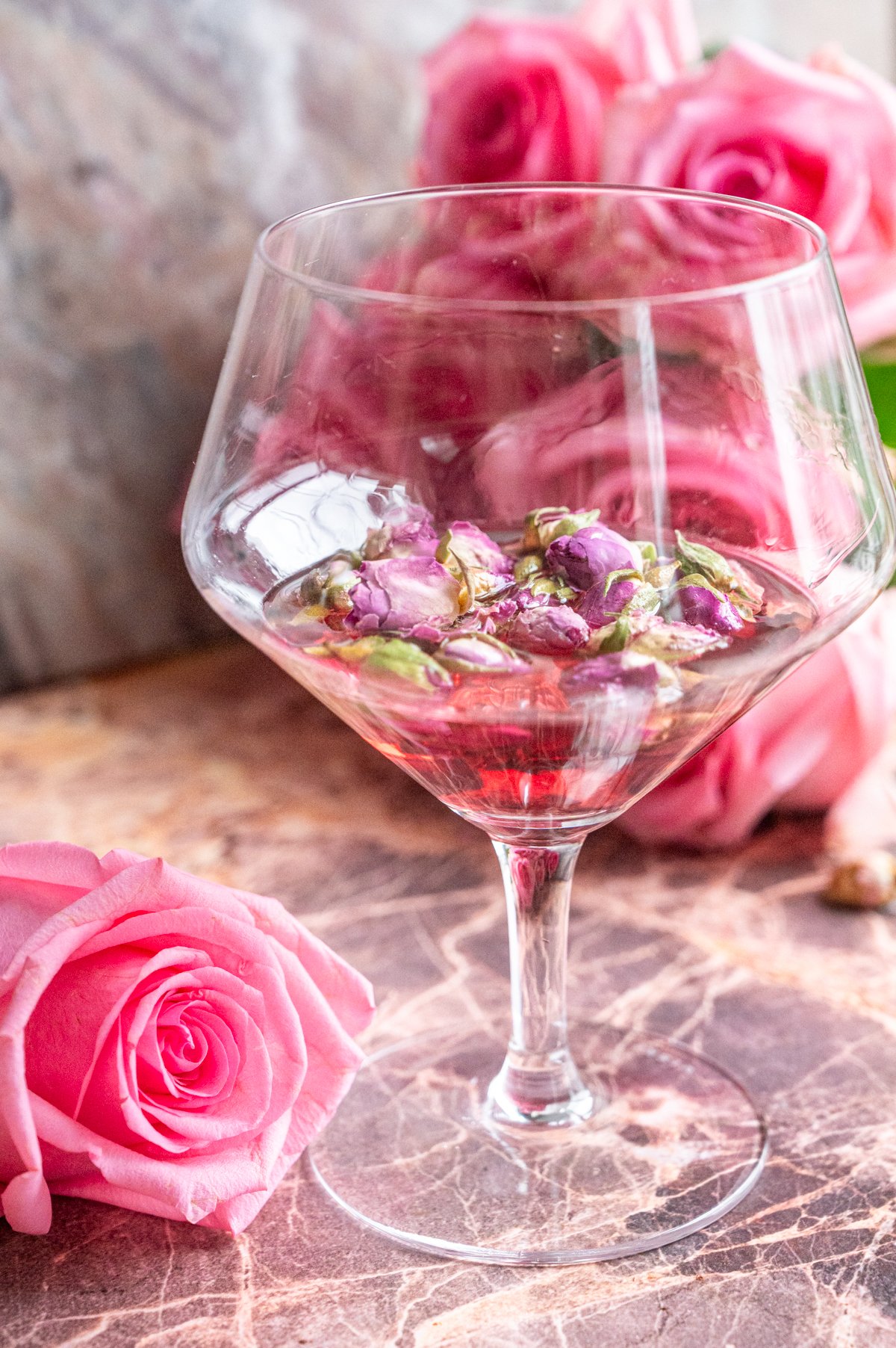 The rose bud tea and the gin sitting in a gin and tonic glass.