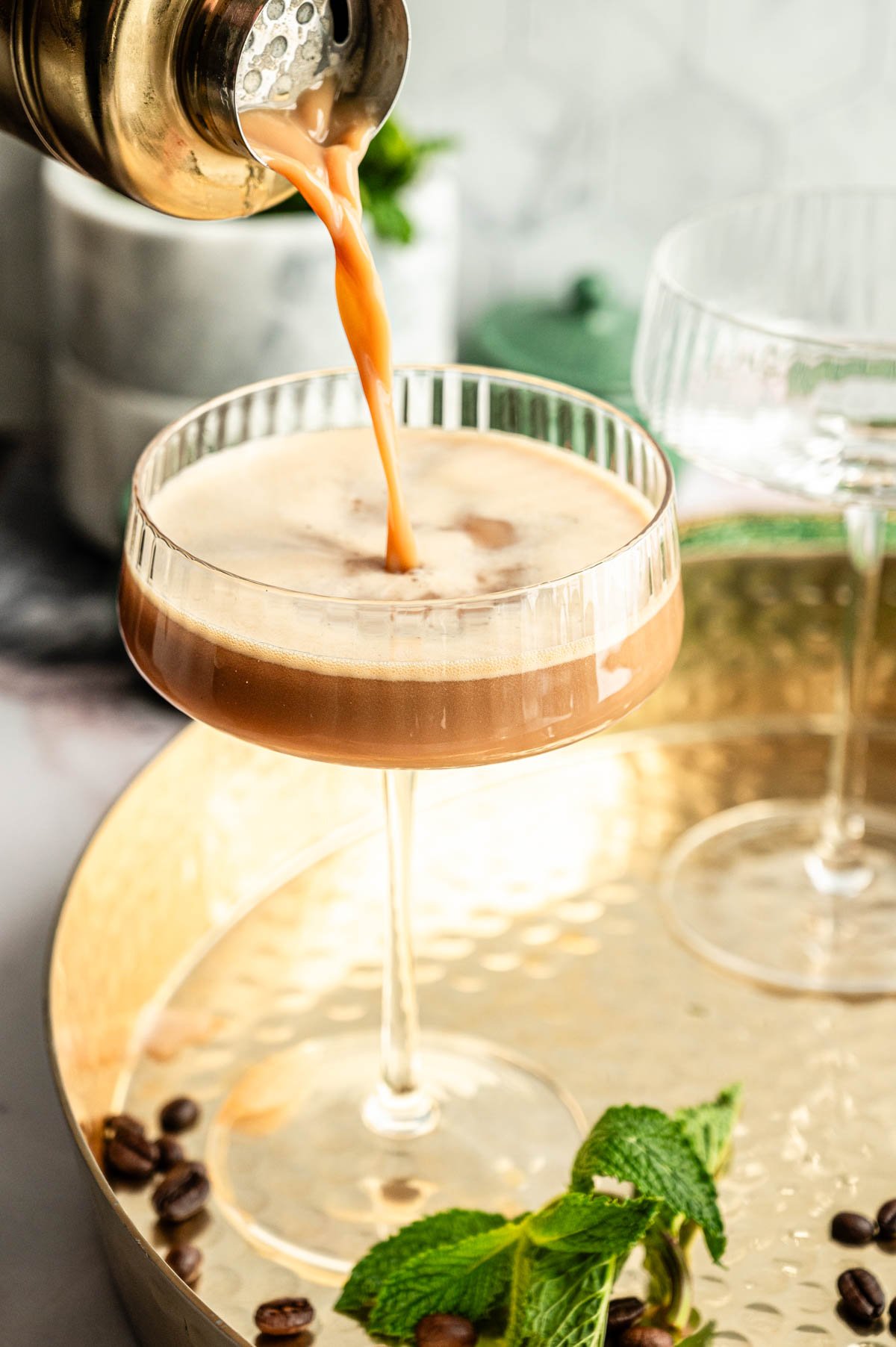 The cocktail is being poured into a martini glass.