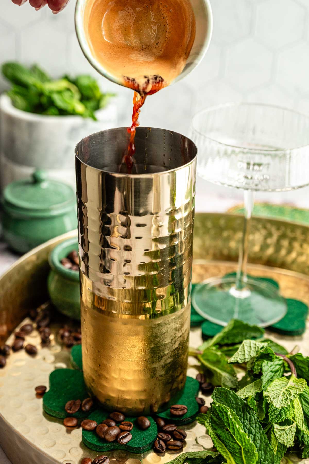 Espresso being poured into a gold cocktail shaker.