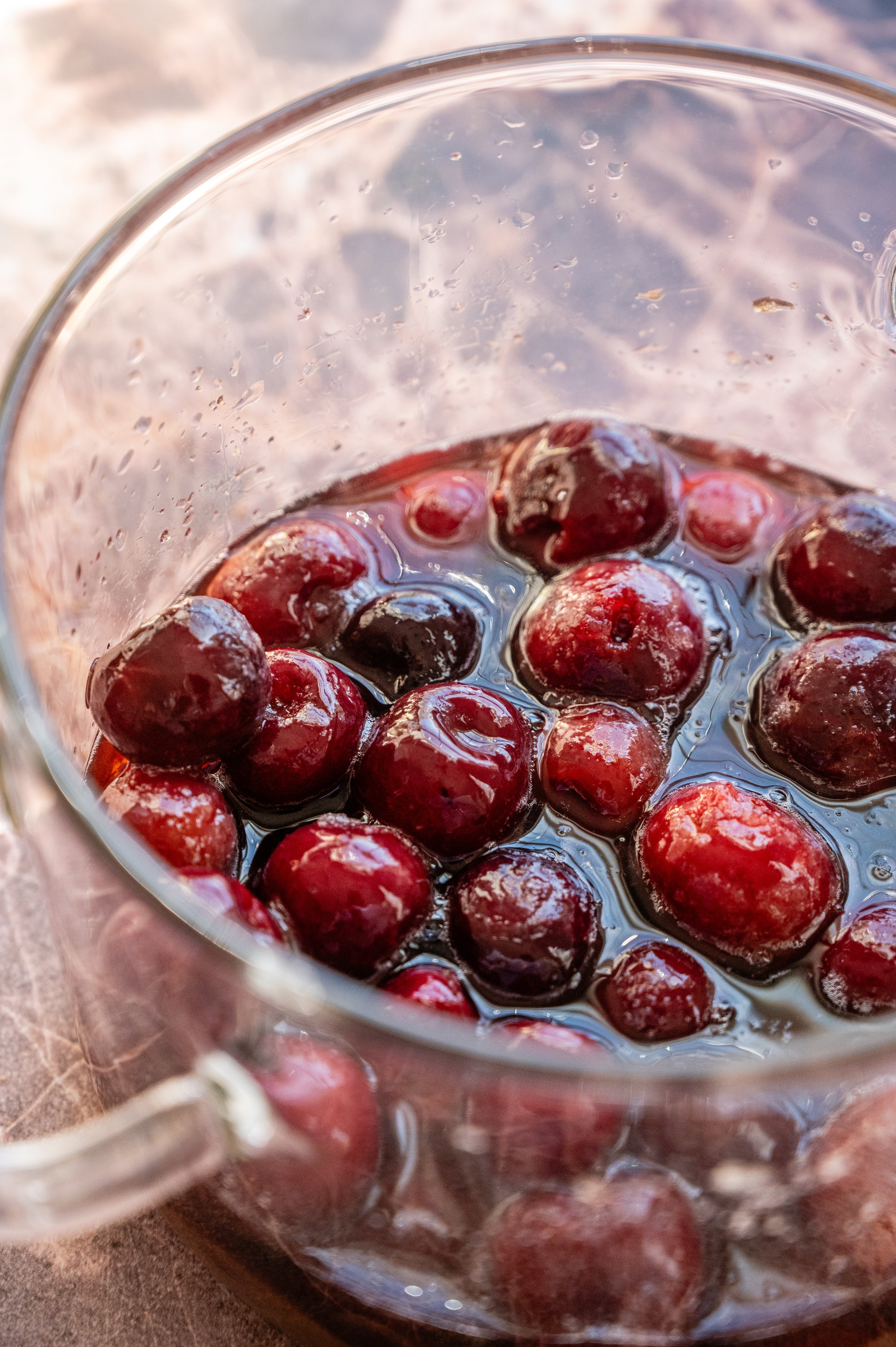 Cherries, sugar, and water in glass pot.