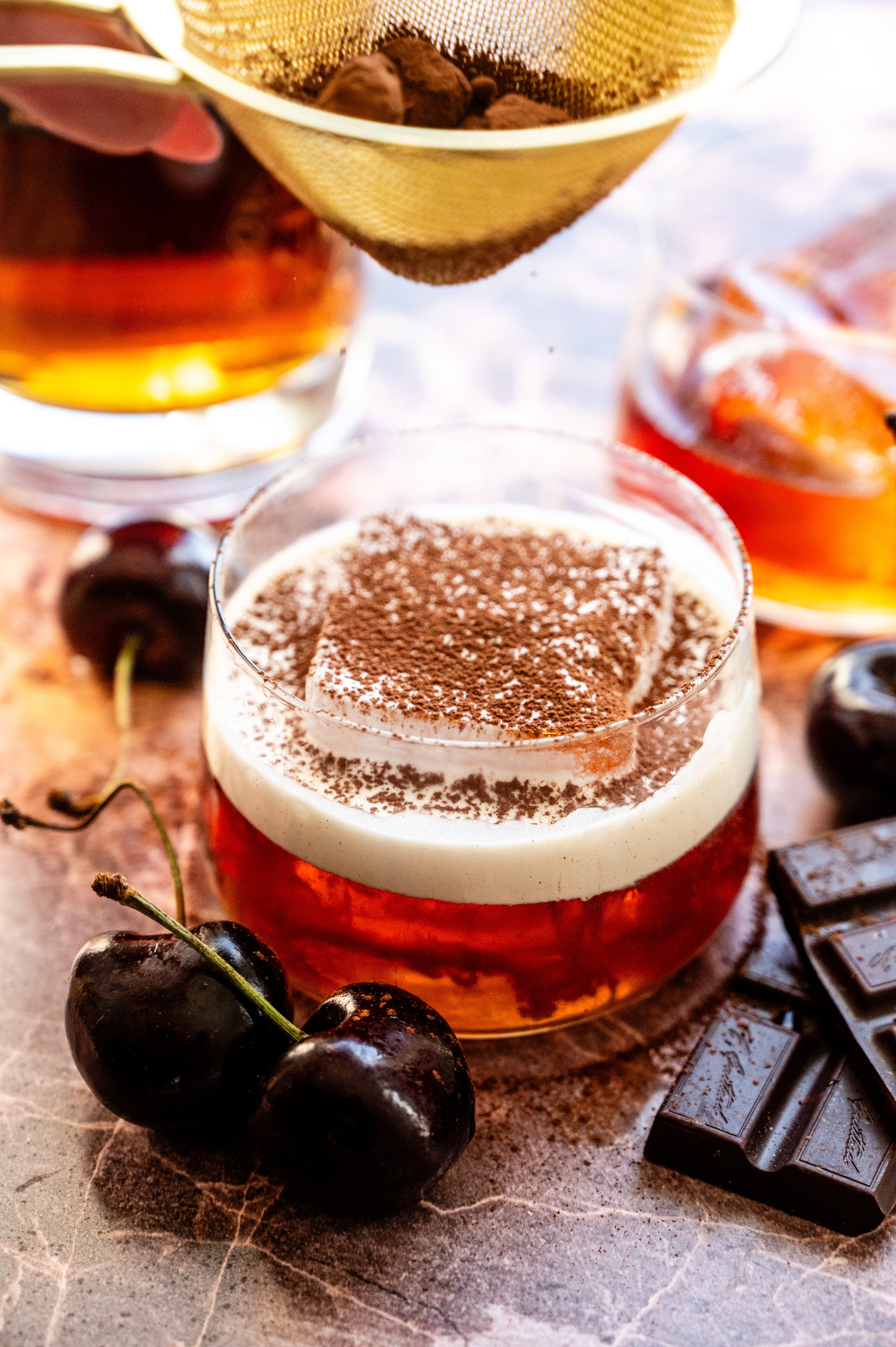 The cream has been poured on top of the drink and it is being dusted with chocolate.