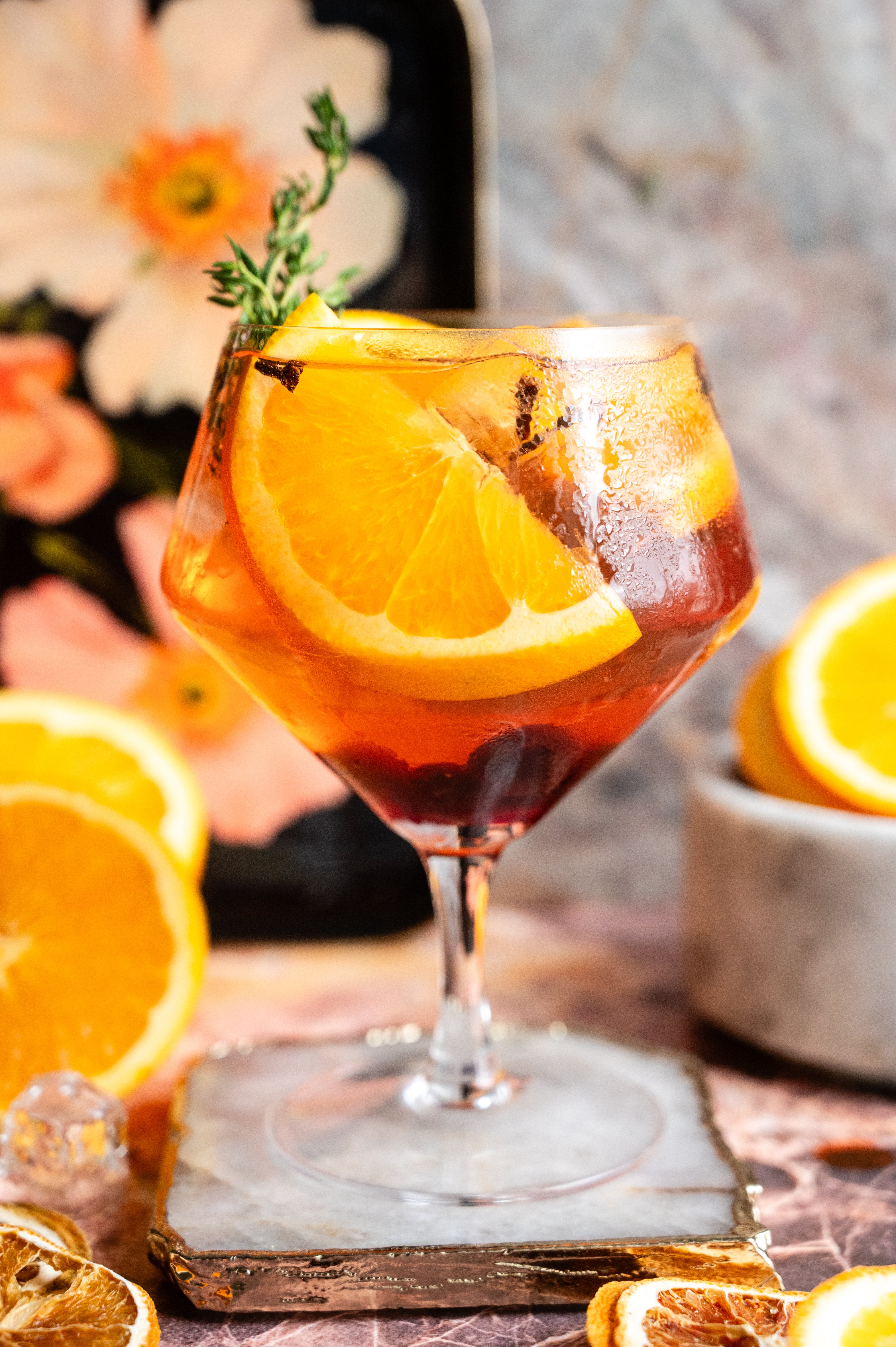 A large ballon glass filled with the Spanish gin and tonic on a pink marble table.