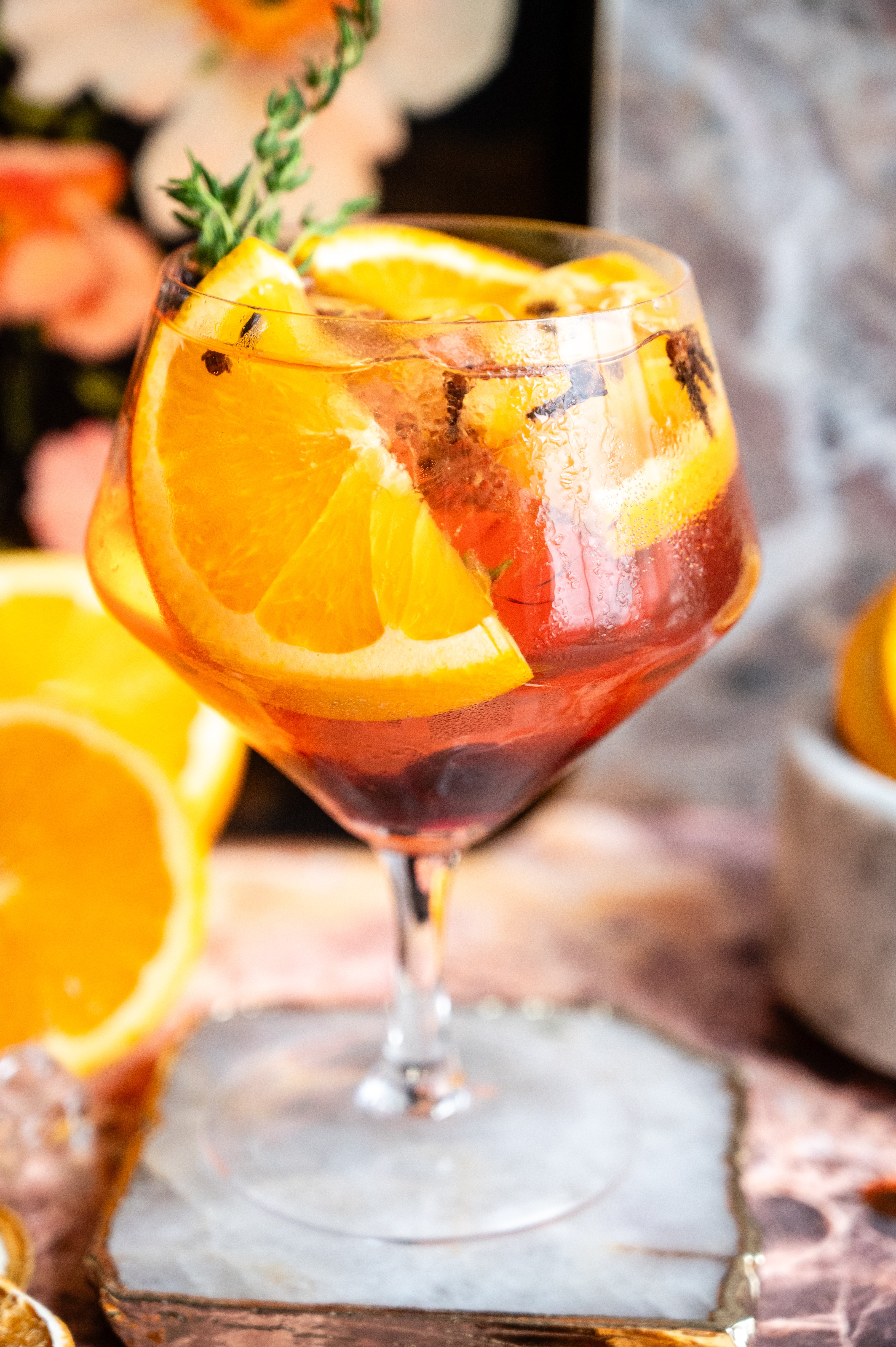 A large ballon glass filled with the Spanish gin and tonic on a pink marble table.