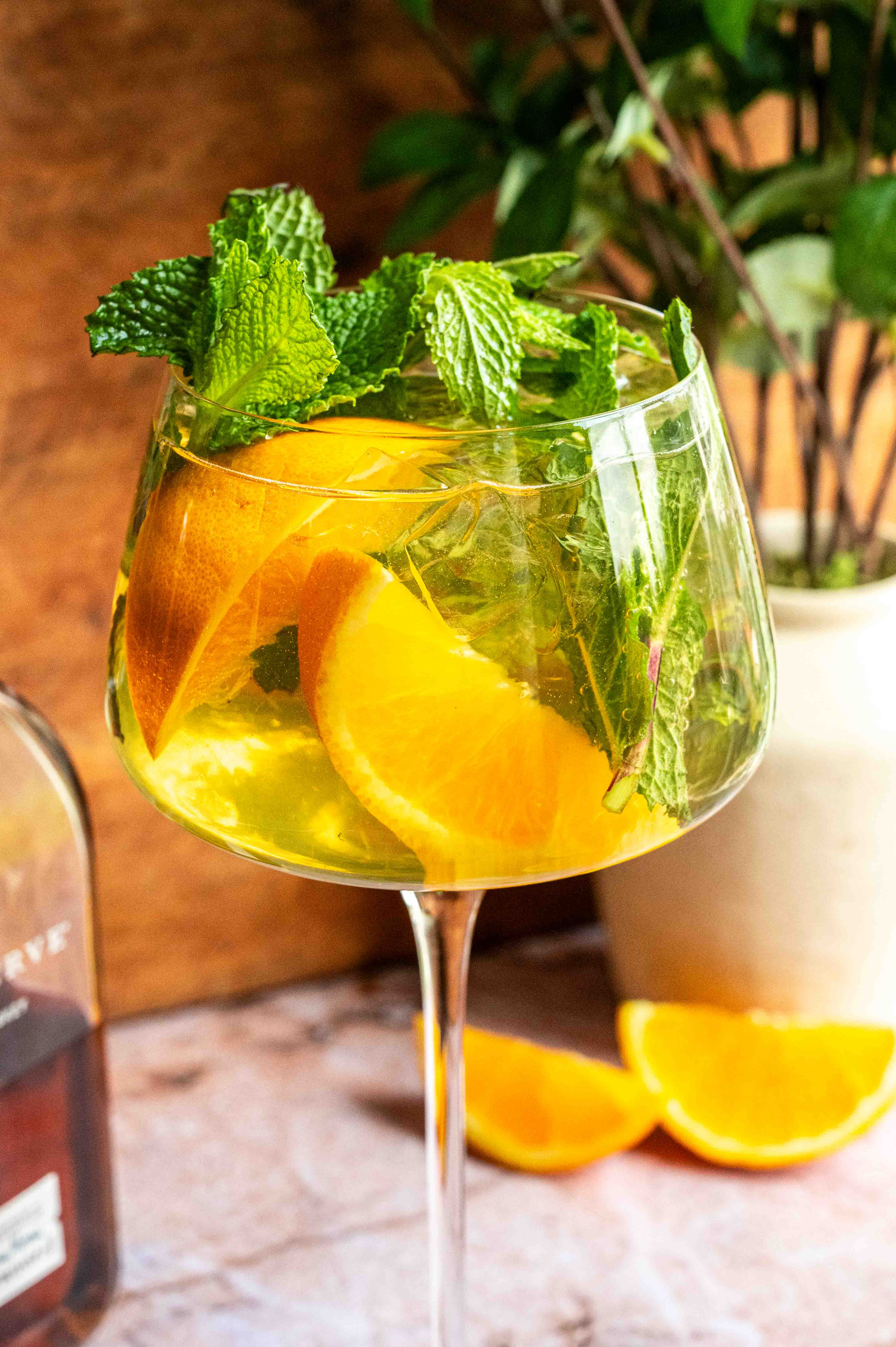 The glass has been garnished with lots of mint and orange slices.