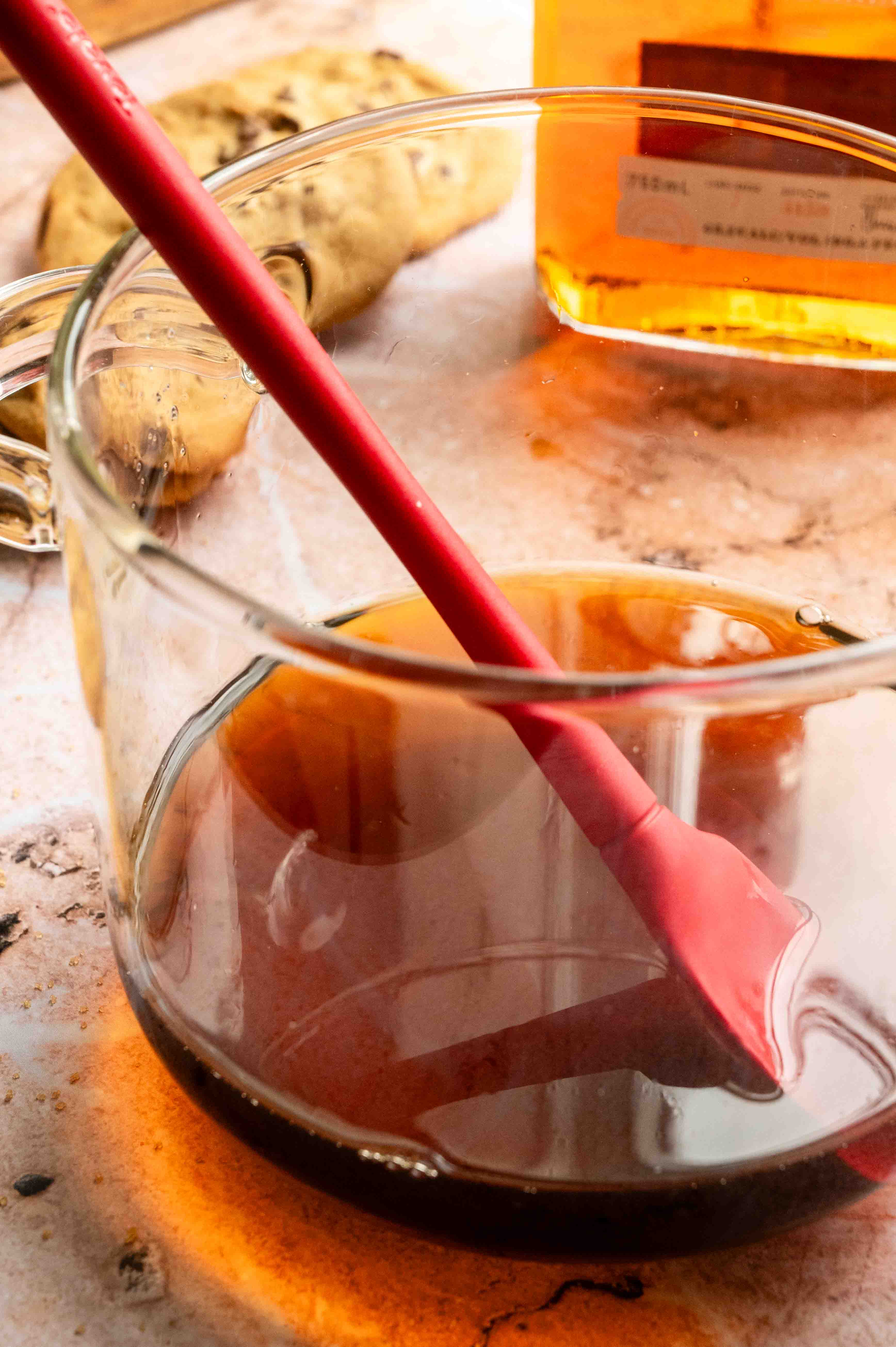 The syrup in a glass pot on a pink marble table.