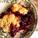 Blackberry cobbler with a biscuit topping in a green floral bowl.