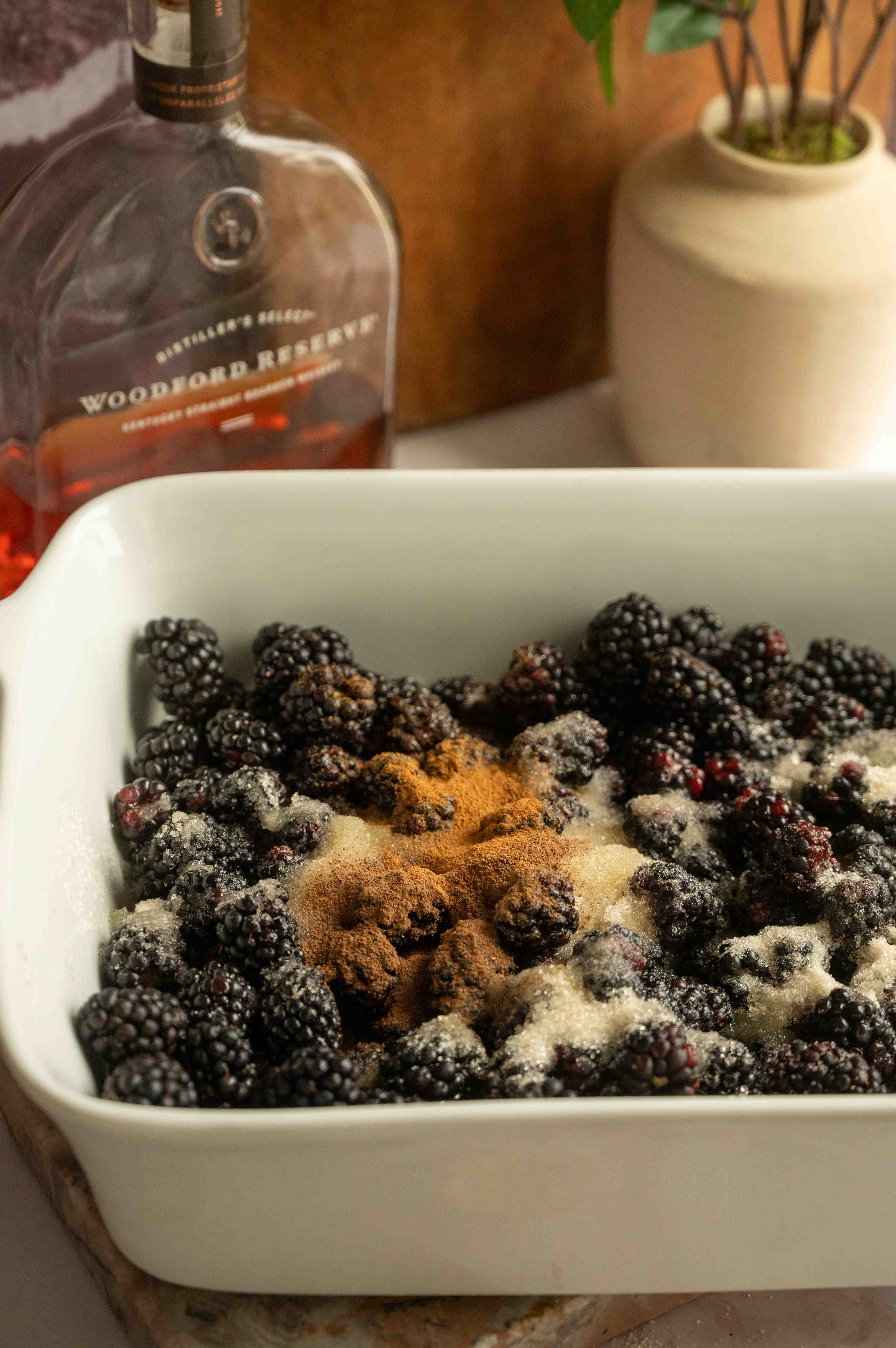 The blackberries, sugar, spices, lemon juice, and bourbon in a 9x13 baking tray.