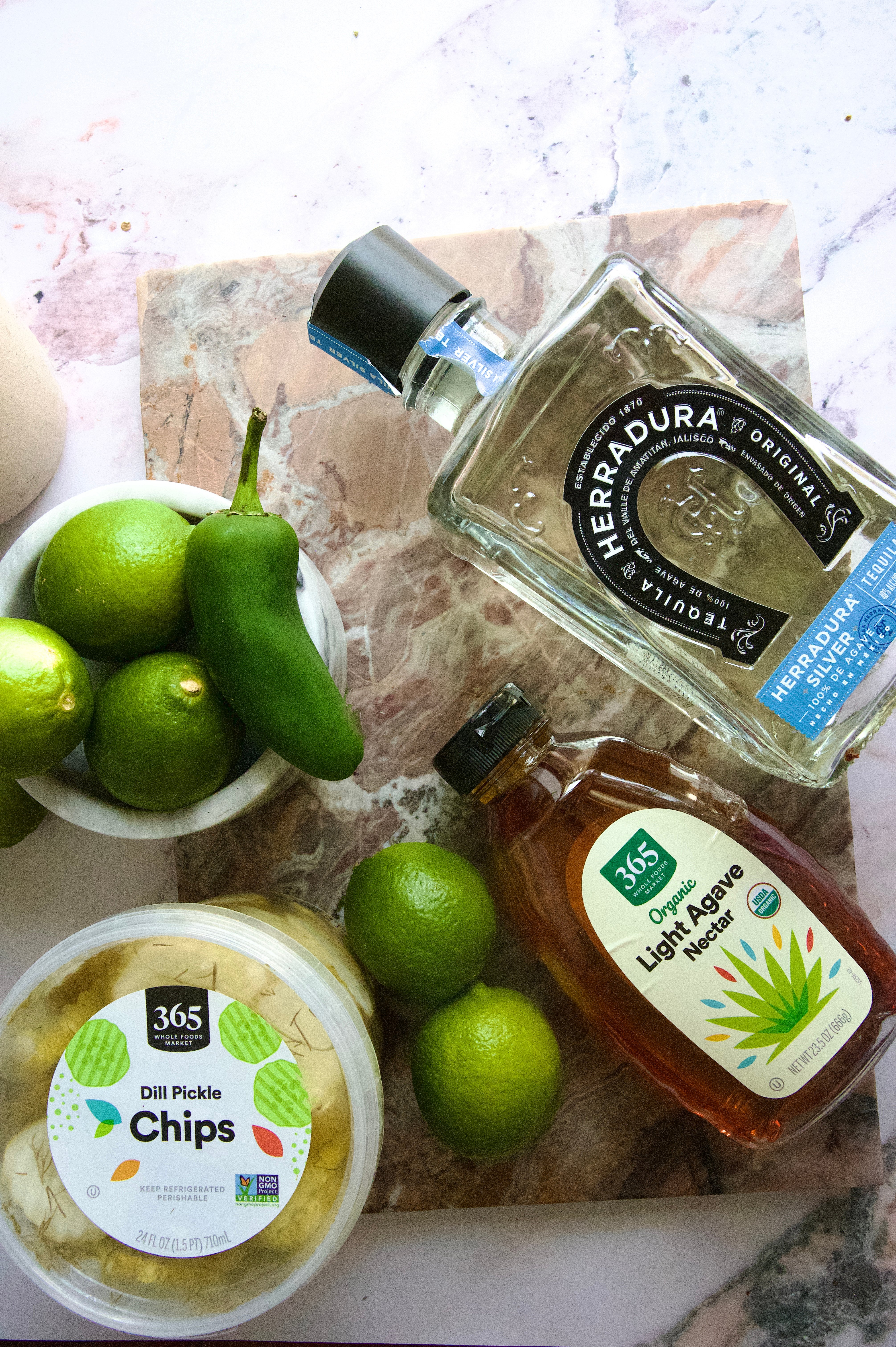 The ingredients for the cocktail on a pink marble table.