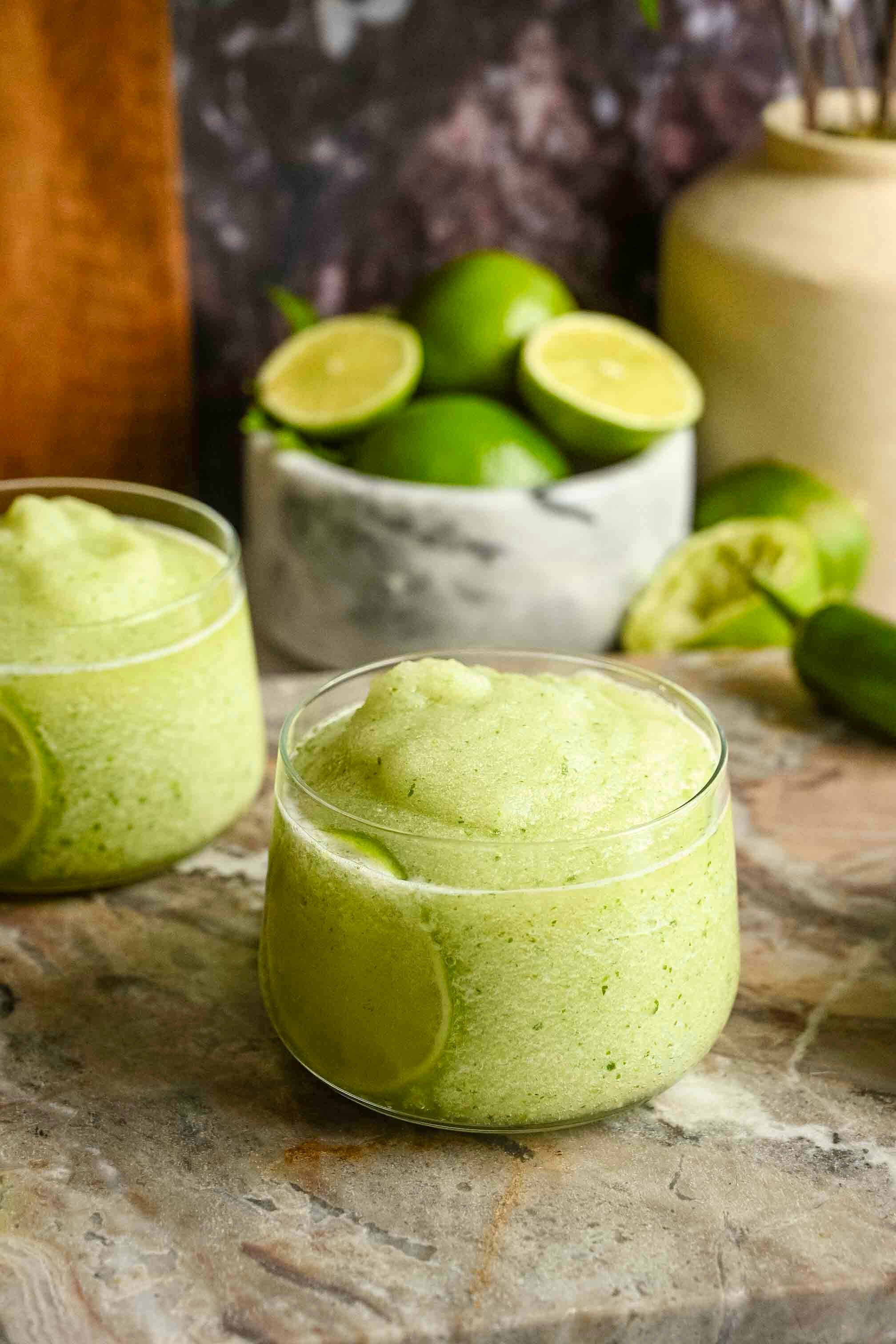 The blended drink has been poured into glasses with a lime slice.