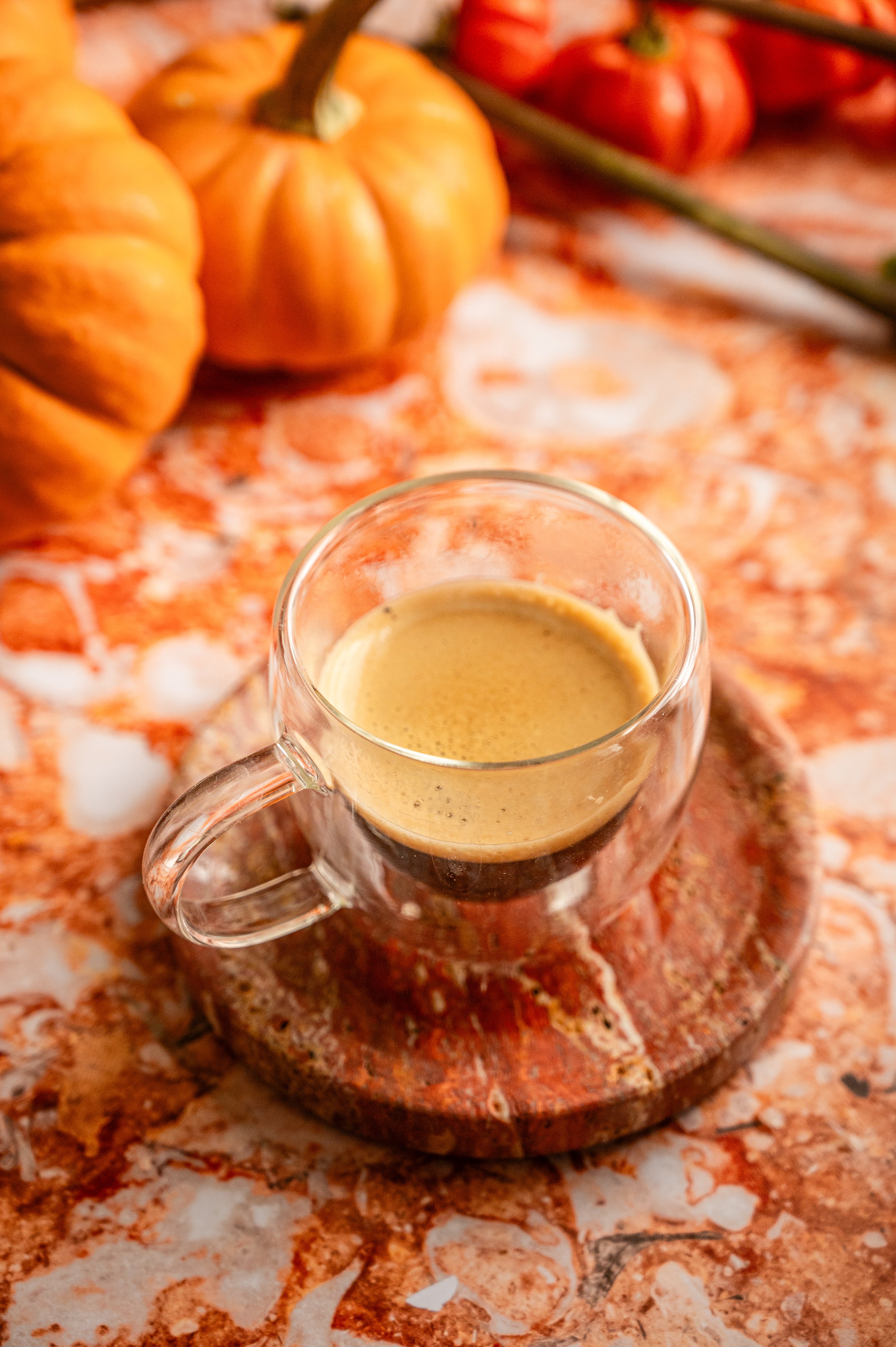 A shot of espresso on a orange marble table.