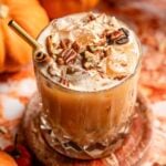 The cocktail topped with chopped pecans and a gold straw.