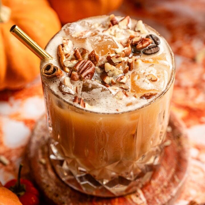The cocktail topped with chopped pecans and a gold straw.