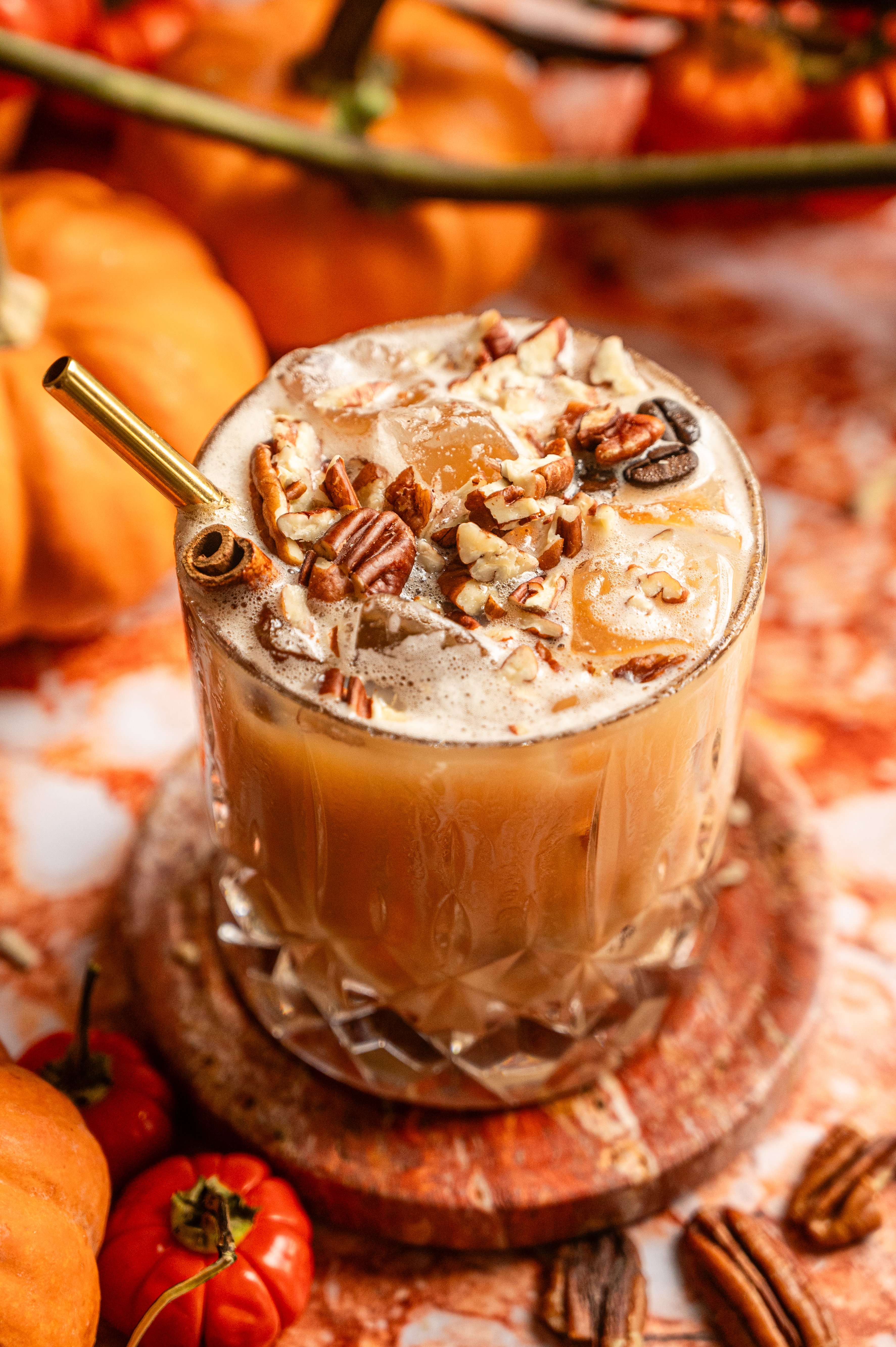 The cocktail topped with chopped pecans and a gold straw.