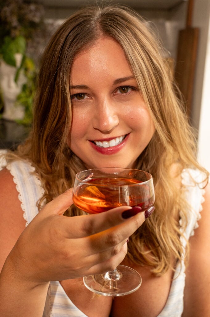 Pate giltner head shot cropped. She is smiling and holding a glass of bourbon.