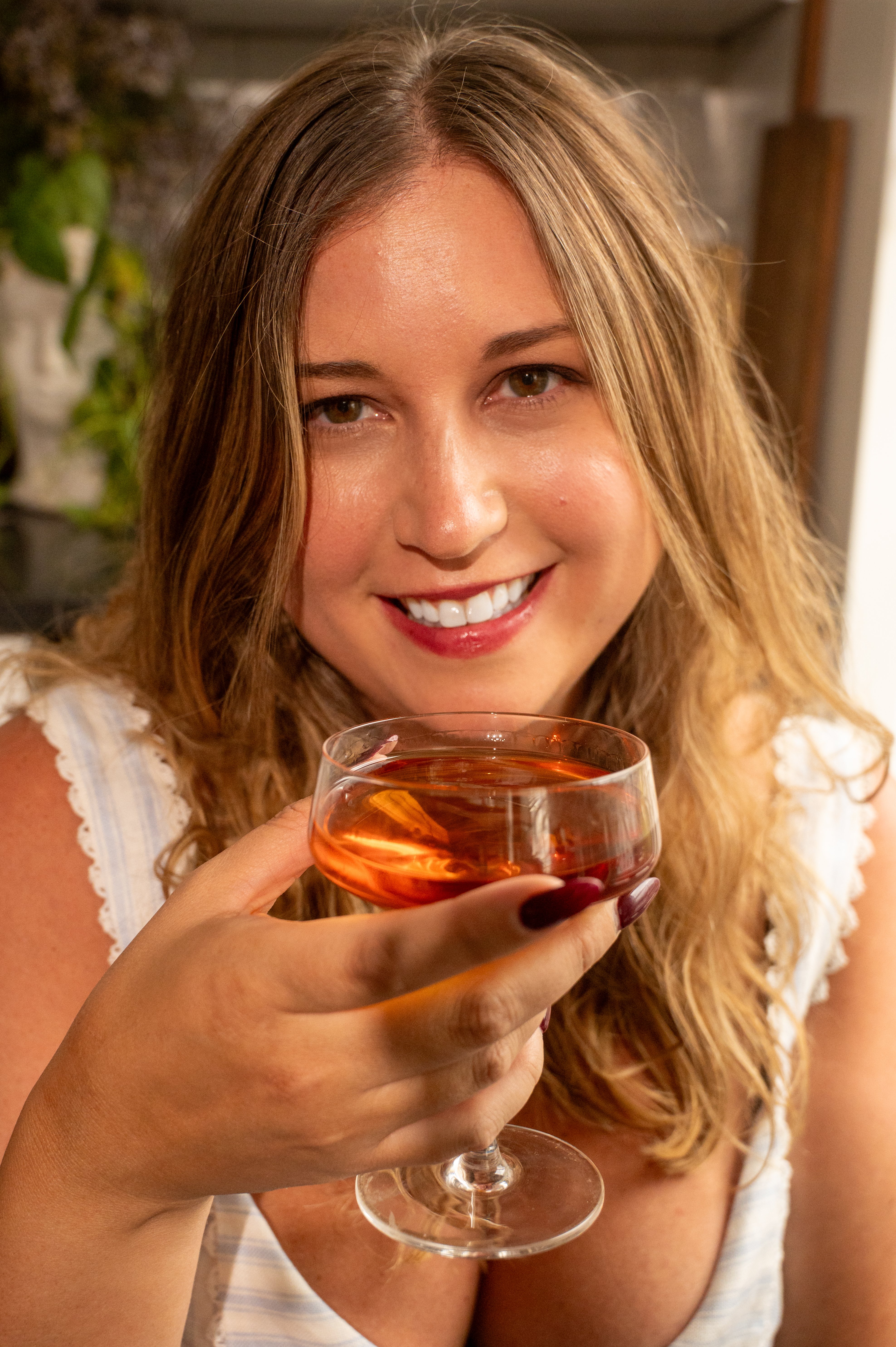 Pate giltner head shot cropped. She is smiling and holding a glass of bourbon.