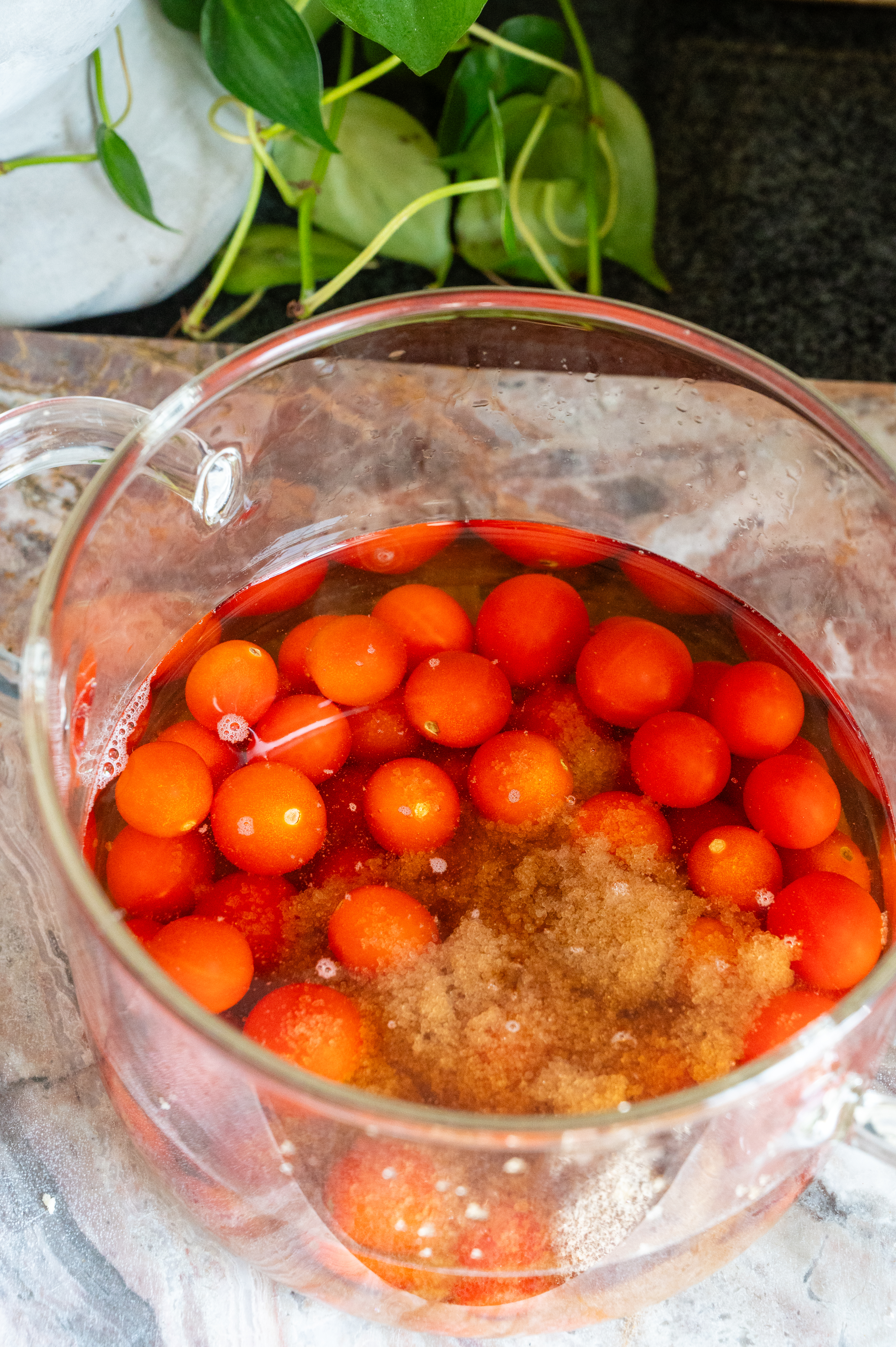 Cherry tomatoes, water, and brown sugar in a glass pot.