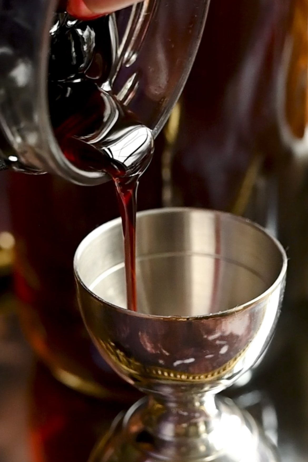 cherry juice being poured into a jigger.