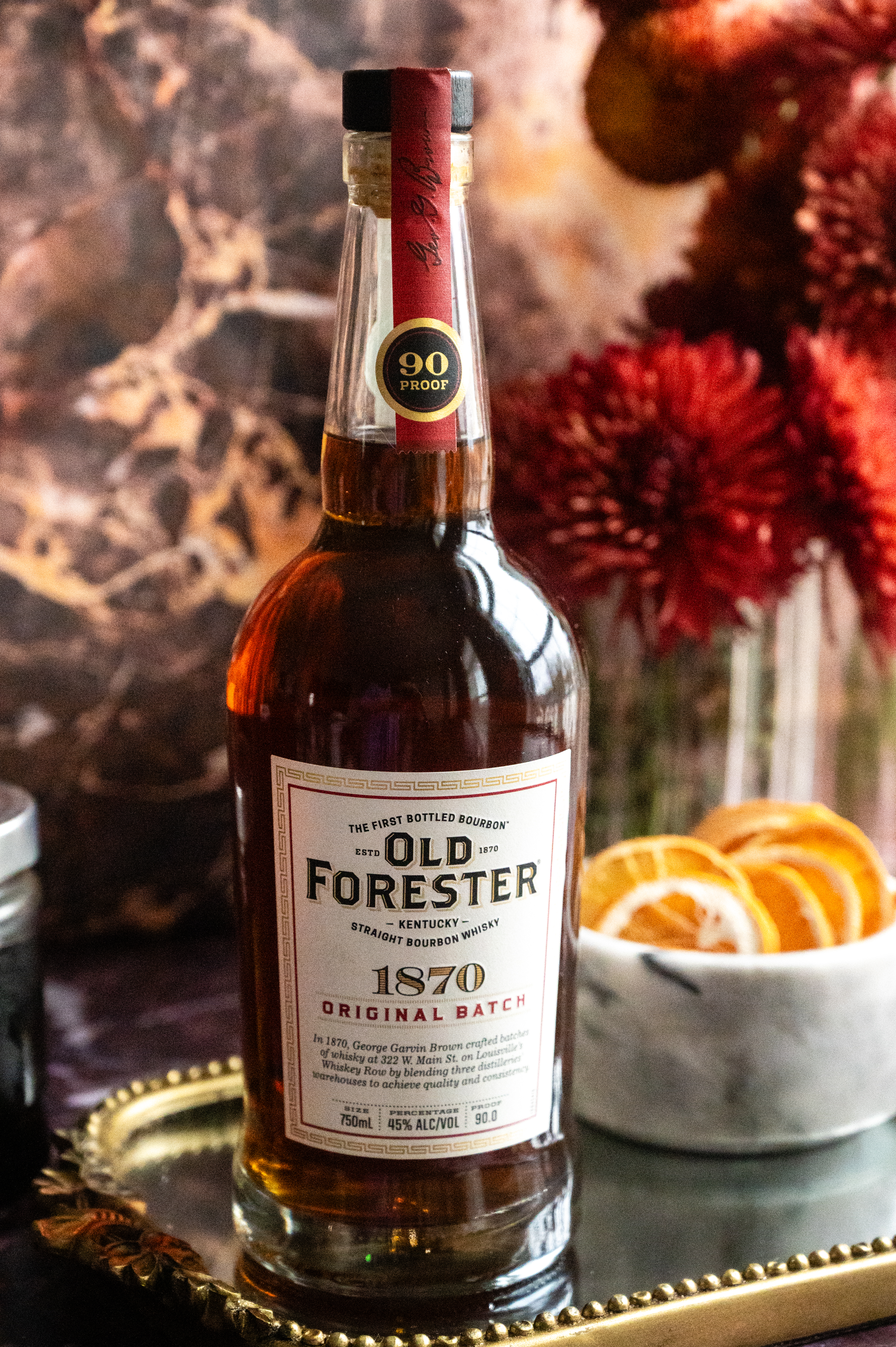 a bottle of old forester 1870 sitting on a mirrored tray.