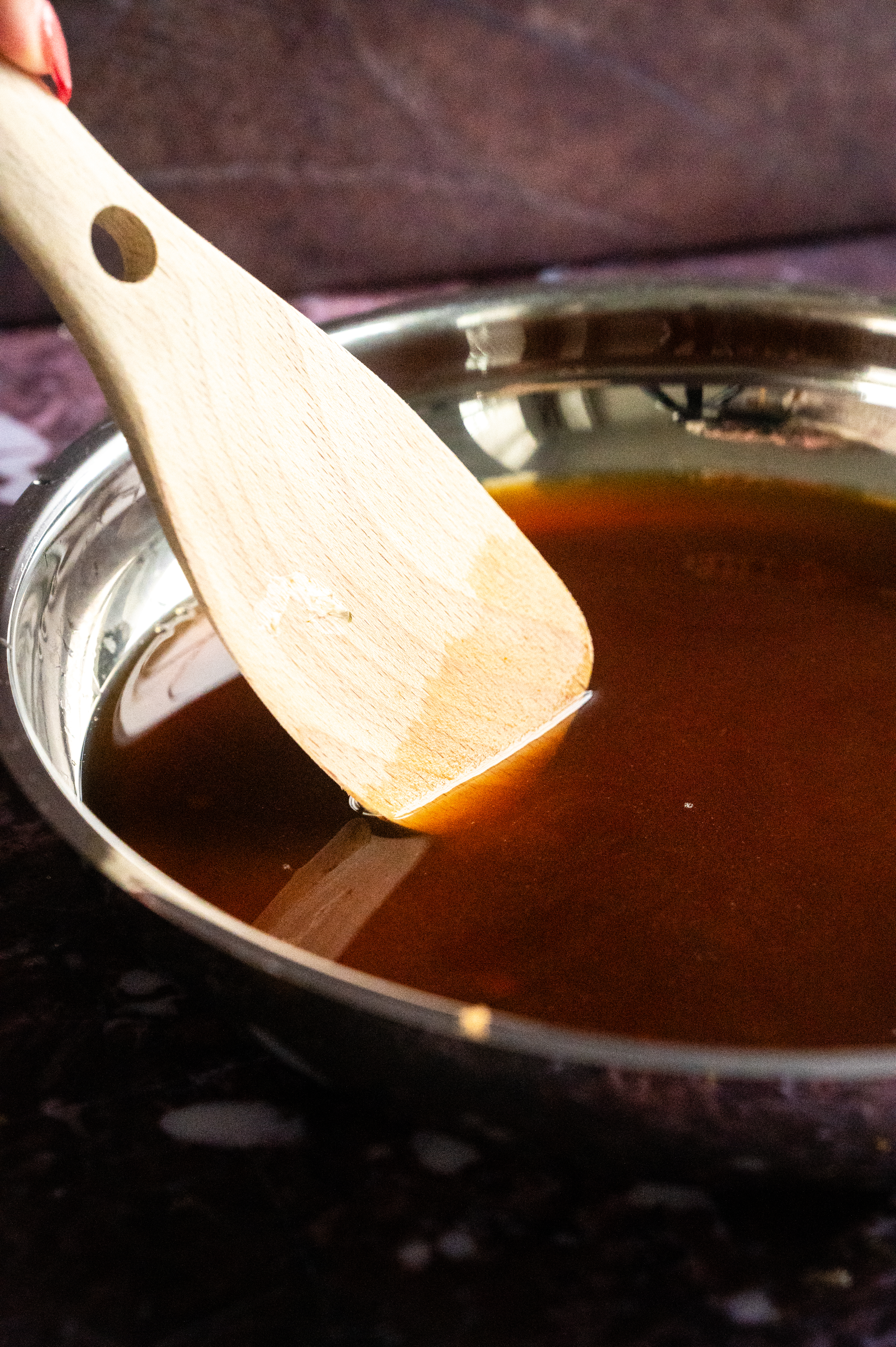 A sauce pan with wodden spoon stirring syrup.