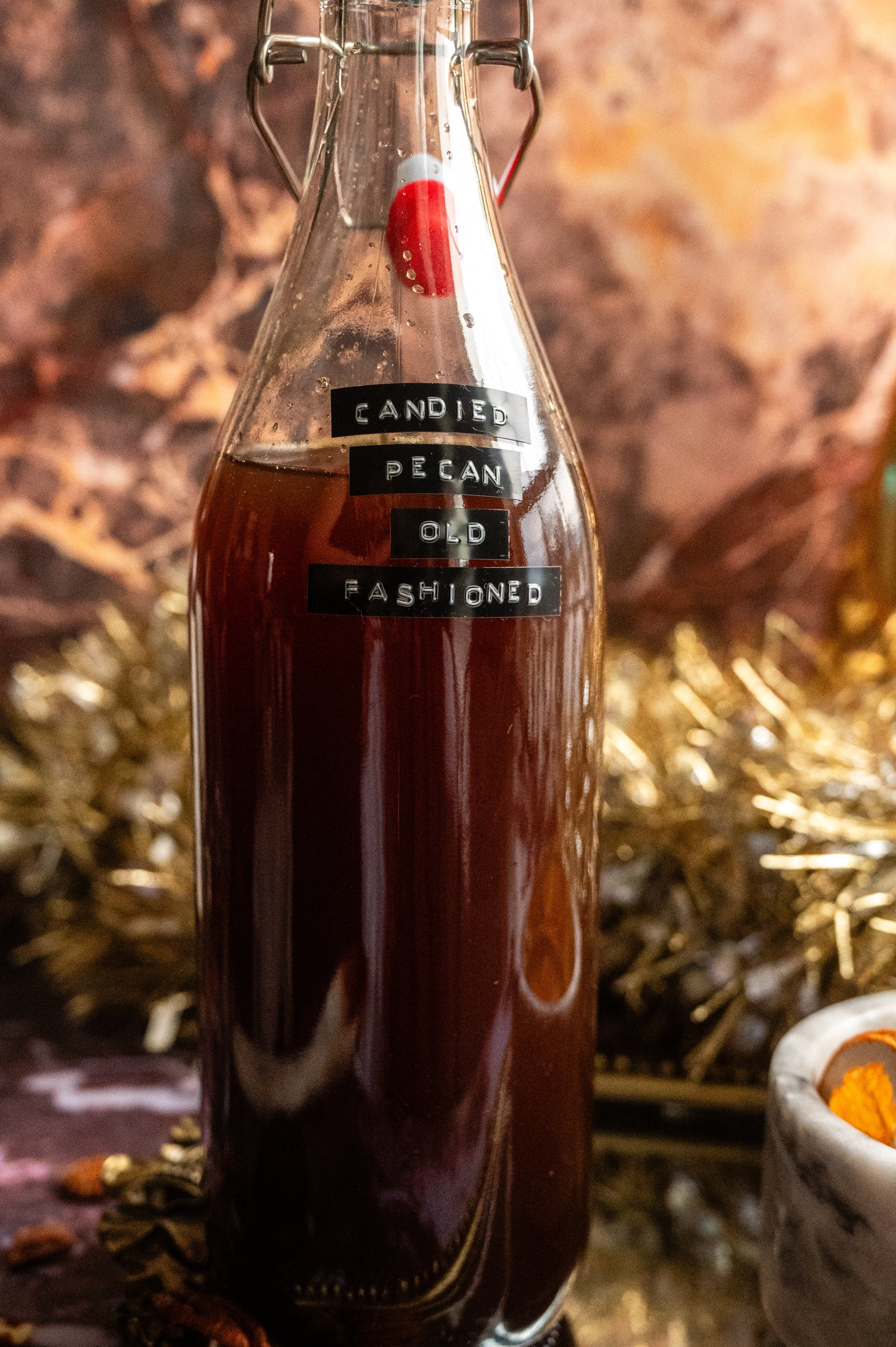 The bourbon and and syrup have been added to a 32 ounce glass bottle.