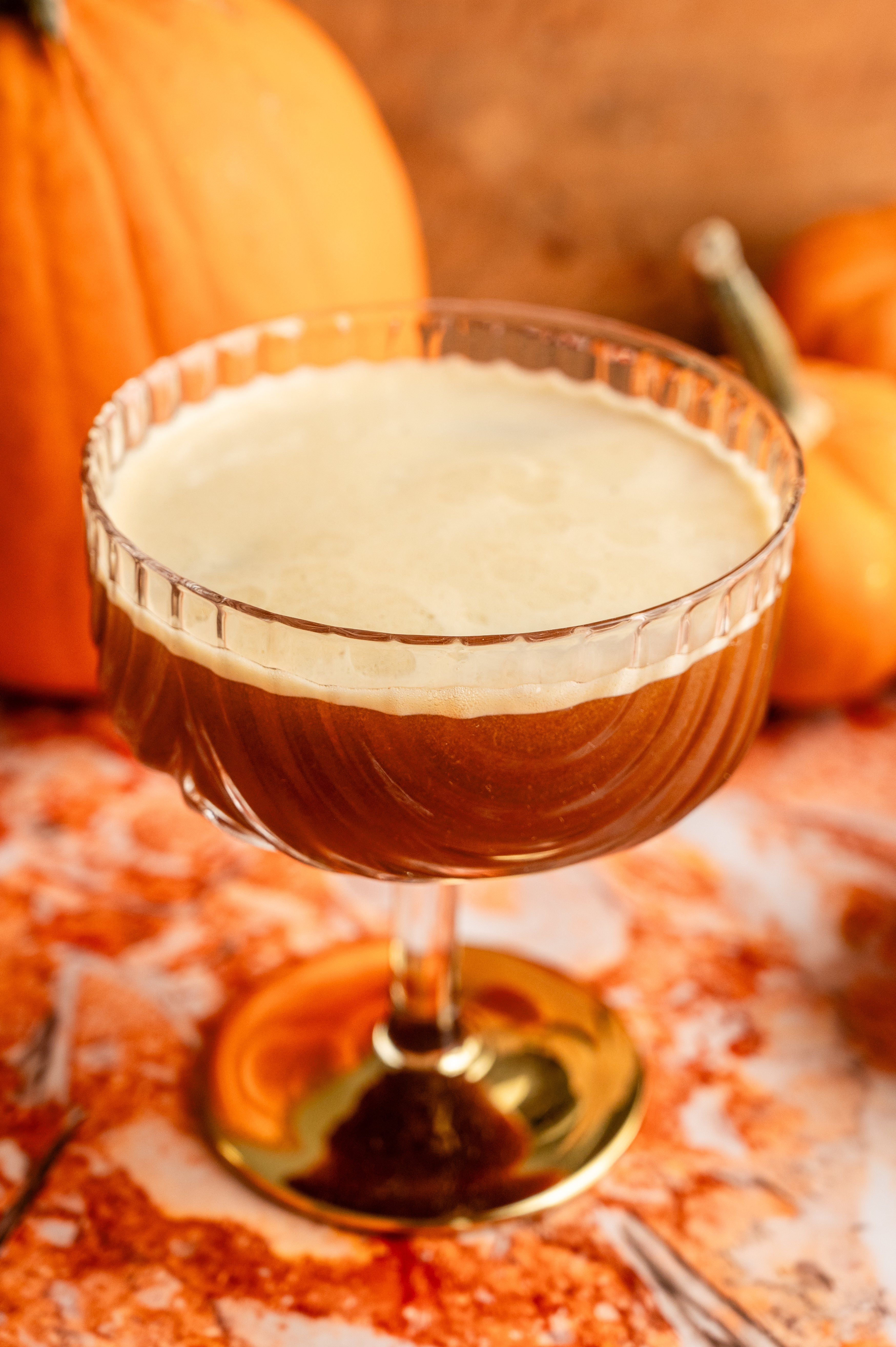 The cocktail poured into a coupe glass with a gold bottom.